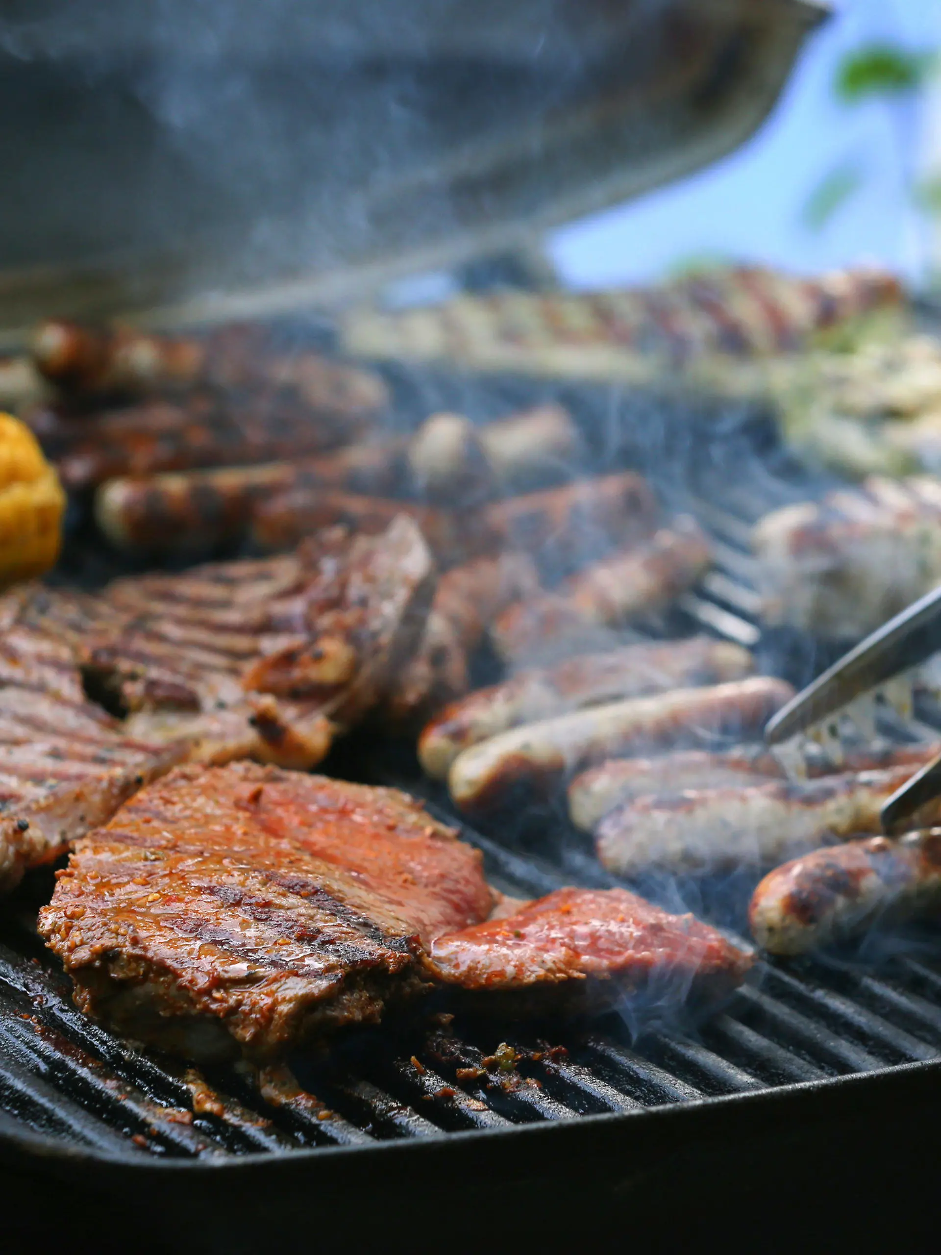 ARCHIV - 26.05.2018, Bayern, München: Maiskolben, Fleischspieße, Bratwürste und Steaks liegen auf dem Rost eines Gasgrills.   (zu dpa «Schweinenackensteak beliebtes Grillfleisch - Spezialitäten im Kommen» vom 04.08.2018) Foto: Karl-Josef Hildenbrand/dpa +++ dpa-Bildfunk +++