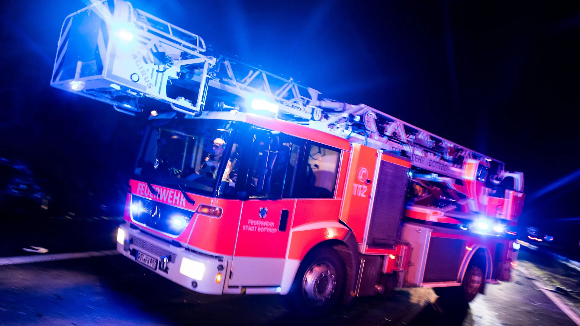 ARCHIV - 21.01.2018, Nordrhein-Westfalen, Bottrop: ILLUSTRATION - Ein Drehleiterwagen der Feuerwehr fährt mit Blaulicht an einer Unfallstelle vorbei. Der Verband der Feuerwehren in NRW trifft sich zu Sondersitzung in Wuppertal. Foto: Marcel Kusch/dpa +++ dpa-Bildfunk +++