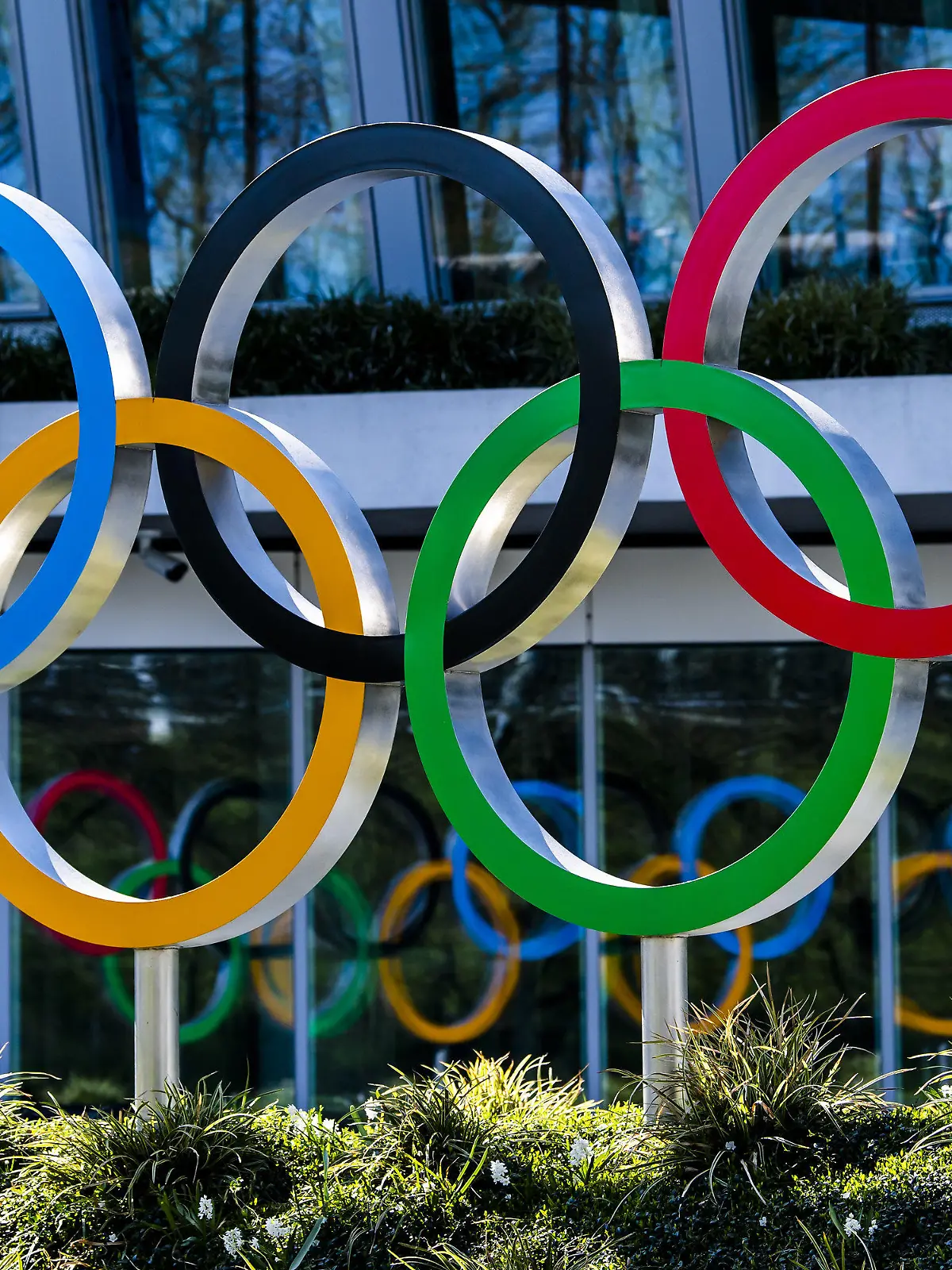 24.03.2020, Schweiz, Lausanne: Die Olympischen Ringe werden am Eingang des IOC, dem Sitz des Internationalen Olympischen Komitees, in Lausanne ausgestellt. Die Olympischen Spiele in Tokio sollen verschoben werden, spätestens aber im Sommer 2021 stattfinden. Das haben das Internationale Olympische Komitee und die Olympia-Organisatoren in Japan gemeinsam am Dienstag beschlossen, wie das IOC mitteilte. Foto: Jean-Christophe Bott/KEYSTONE/dpa +++ dpa-Bildfunk +++