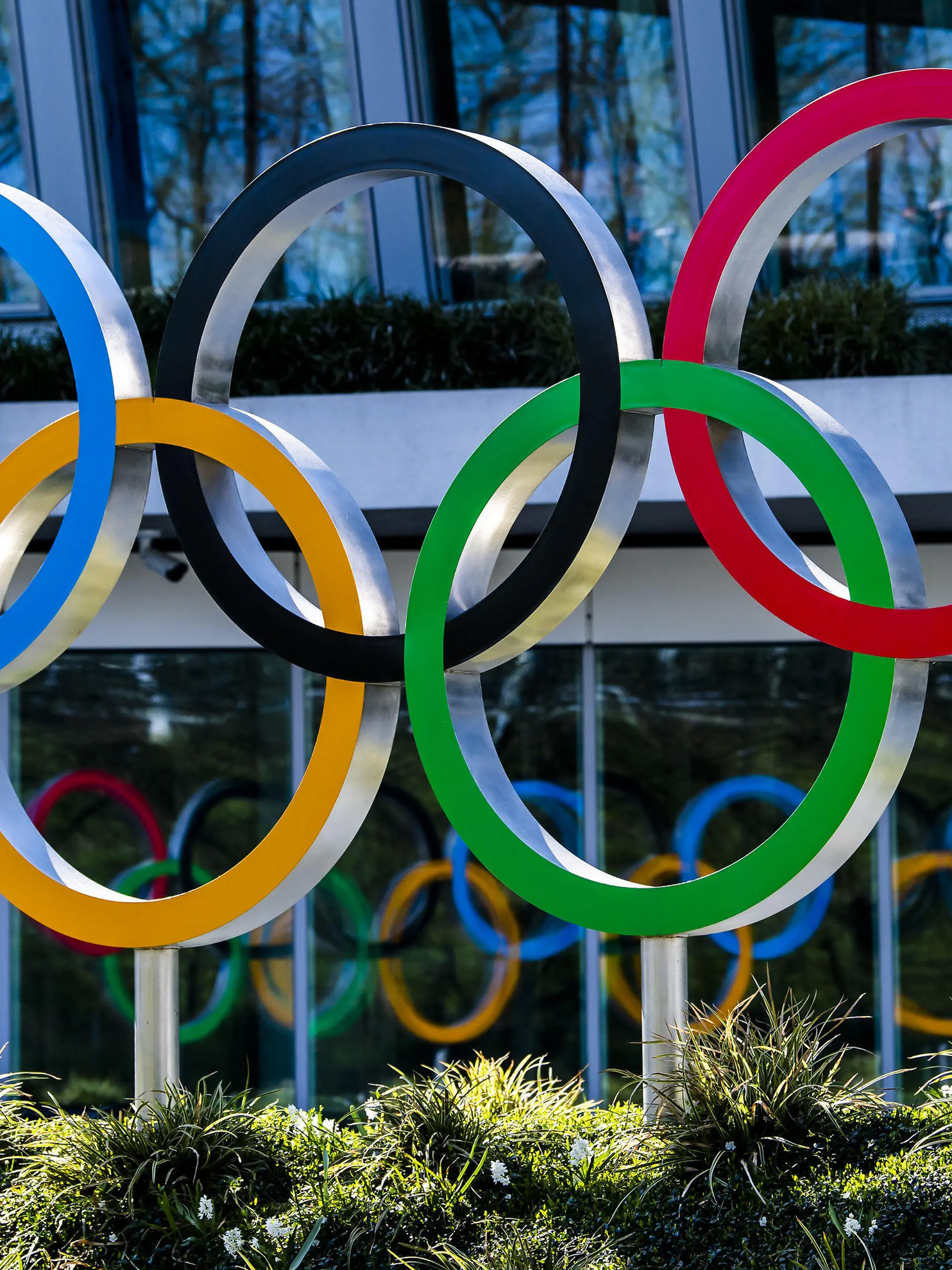 24.03.2020, Schweiz, Lausanne: Die Olympischen Ringe werden am Eingang des IOC, dem Sitz des Internationalen Olympischen Komitees, in Lausanne ausgestellt. Die Olympischen Spiele in Tokio sollen verschoben werden, spätestens aber im Sommer 2021 stattfinden. Das haben das Internationale Olympische Komitee und die Olympia-Organisatoren in Japan gemeinsam am Dienstag beschlossen, wie das IOC mitteilte. Foto: Jean-Christophe Bott/KEYSTONE/dpa +++ dpa-Bildfunk +++