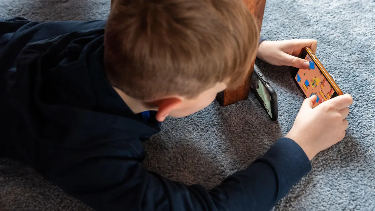 ARCHIV - 20.03.2020, Sachsen;Baden-Württemberg, Dresden: Ein Junge spielt ein Videospiel auf seinem Smartphone und überträgt es mit einem zweiten Handy per Facetime zu seinem Freund. (zu dpa: «Portal soll Eltern sichere Mediennutzung ihrer Kinder erleichtern») Foto: Robert Michael/dpa-Zentralbild/dpa +++ dpa-Bildfunk +++
