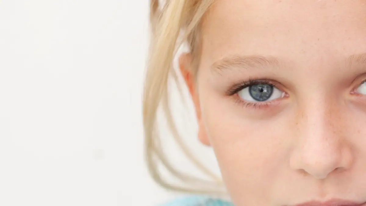 Close up of child with fever thermometer, wrapped in blanket