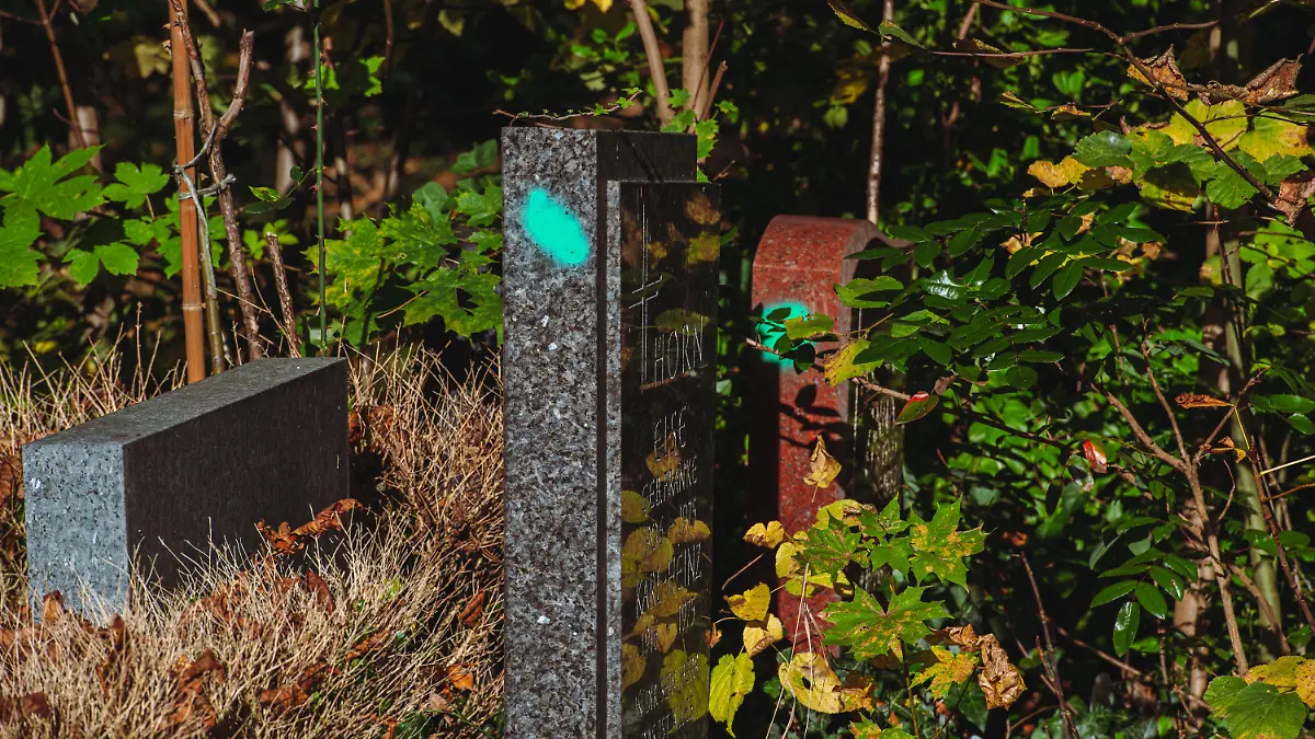 PRODUKTION - 25.10.2021, Berlin: Der grüne Punkt auf dem Grabstein auf dem St. Jacobi Friedhof in Neukölln gibt den Hinweis, dass der Stein ausrangiert wird. In Kursen entstehen auf dem Gelände aus den ehemaligen Grabsteinen Kunst und Gegenstände. Foto: Paul Zinken/dpa +++ dpa-Bildfunk +++