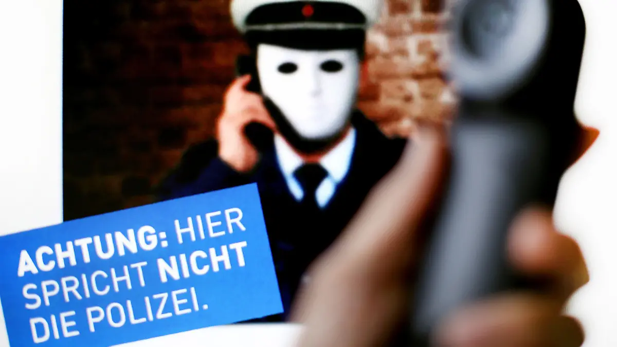 ARCHIV - 11.10.2017, Nordrhein-Westfalen, Düsseldorf: ILLUSTRATION - Ein Telefonhörer ist vor einem Plakat der Polizei mit der Aufschrift «Achtung: Hier spricht NICHT die Polizei» zu sehen. (zu dpa: «Beliebte Masche: Falsche Polizeibeamte richten Millionenschäden an») Foto: Martin Gerten/dpa +++ dpa-Bildfunk +++