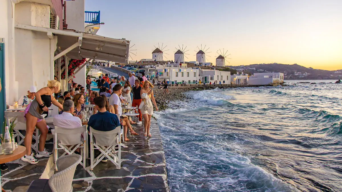 The iconic windmills of Mykonos island as seen from Little Venice with tourists at the bars, cafes and restaurants. Mykonos is an island in Greece in the Aegean sea. There are 16 windmills on the island, 5 of them above Chora, the main town in the island. The windmills were built in the 16th century from the Venetians but their constructions continued until the 20th century. Sunset with people at the windmills in Mykonos. Tourists enjoy a beautiful sunset during the magic hour at Mykonos island in Greece. The Greek island of Myconos is a popular glamorous Mediterranean travel destination for holidays in the Cyclades, Aegean Sea with the iconic whitewashed buildings, the sandy beaches and famous party at the beach bars. The tourism and travel industry had a negative impact in the business and local economy sector due to the Covid-19 Coronavirus pandemic. Mykonos island, Greece(Photo by Nicolas Economou/NurPhoto)