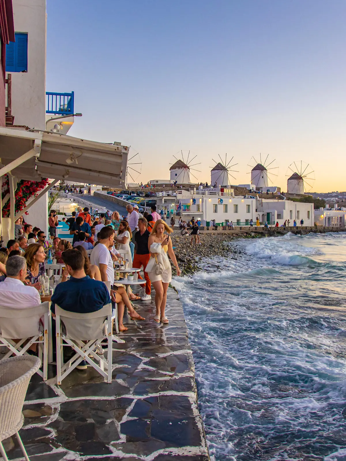The iconic windmills of Mykonos island as seen from Little Venice with tourists at the bars, cafes and restaurants. Mykonos is an island in Greece in the Aegean sea. There are 16 windmills on the island, 5 of them above Chora, the main town in the island. The windmills were built in the 16th century from the Venetians but their constructions continued until the 20th century. Sunset with people at the windmills in Mykonos. Tourists enjoy a beautiful sunset during the magic hour at Mykonos island in Greece. The Greek island of Myconos is a popular glamorous Mediterranean travel destination for holidays in the Cyclades, Aegean Sea with the iconic whitewashed buildings, the sandy beaches and famous party at the beach bars. The tourism and travel industry had a negative impact in the business and local economy sector due to the Covid-19 Coronavirus pandemic. Mykonos island, Greece(Photo by Nicolas Economou/NurPhoto)