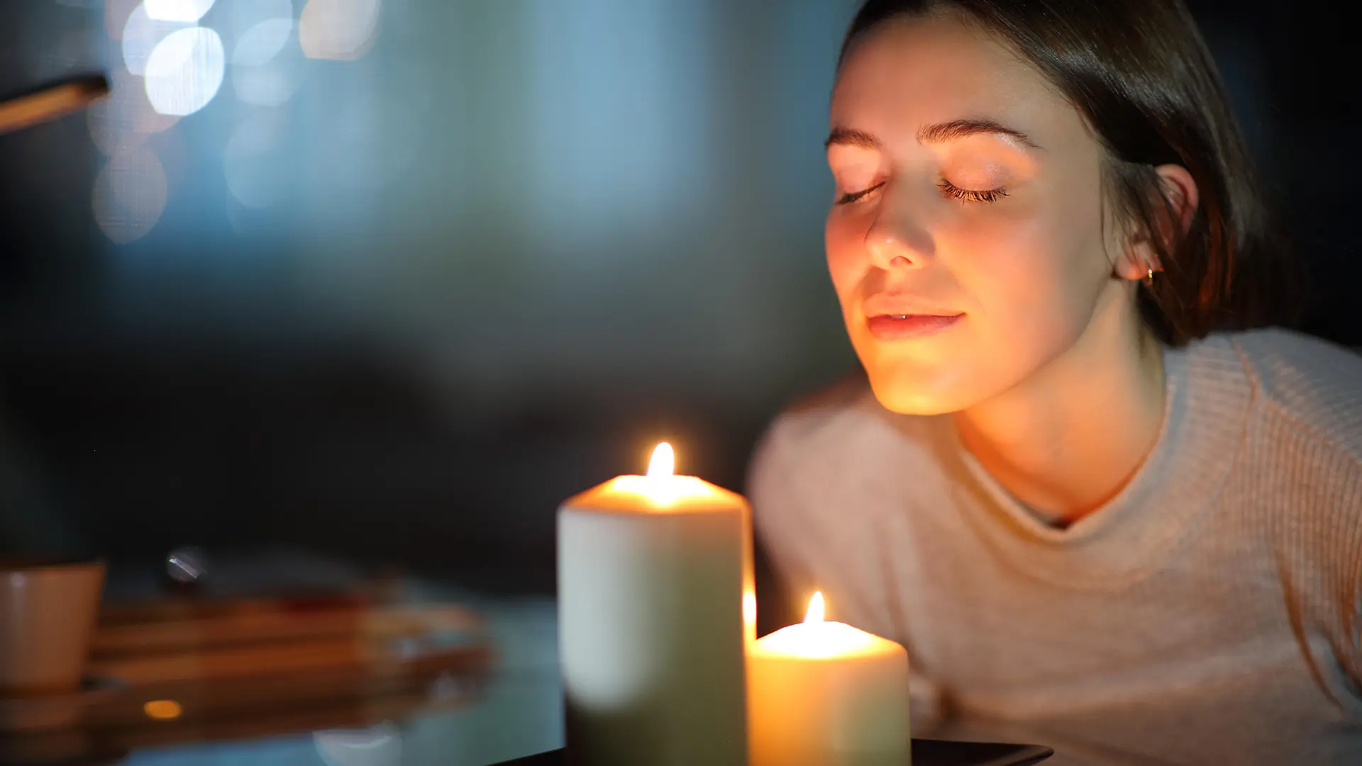 Woman smelling a lighted candle in the night