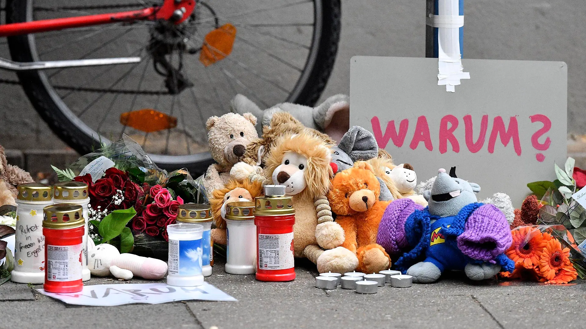 FILE-Teddy bears and candles are pictured at the entrance of an apartment building where five dead children were found in Solingen, Germany, Friday, Sept. 4, 2020. A 28-year-old German mother has been found guilty and sentenced to life in prison for the murder of five of her six children at their home in the western city of Solingen.  (AP Photo/Martin Meissner)