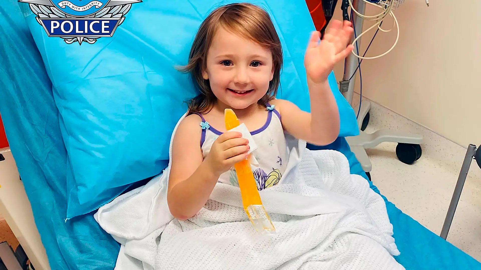 ADDS LOCATION - In this photo provided by the Western Australia Police, four-year-old Cleo Smith waves as she sits on a bed in hospital, Wednesday, Nov. 3, 2021, in Carnarvon, western Australia. Police smashed their way into a suburban house on Wednesday and rescued Cleo whose disappearance from her family's camping tent on Australia's remote west coast more than two weeks ago both horrified and captivated the nation. The seal of Western Australia Police is seen at top left. (Western Australia Police via AP)