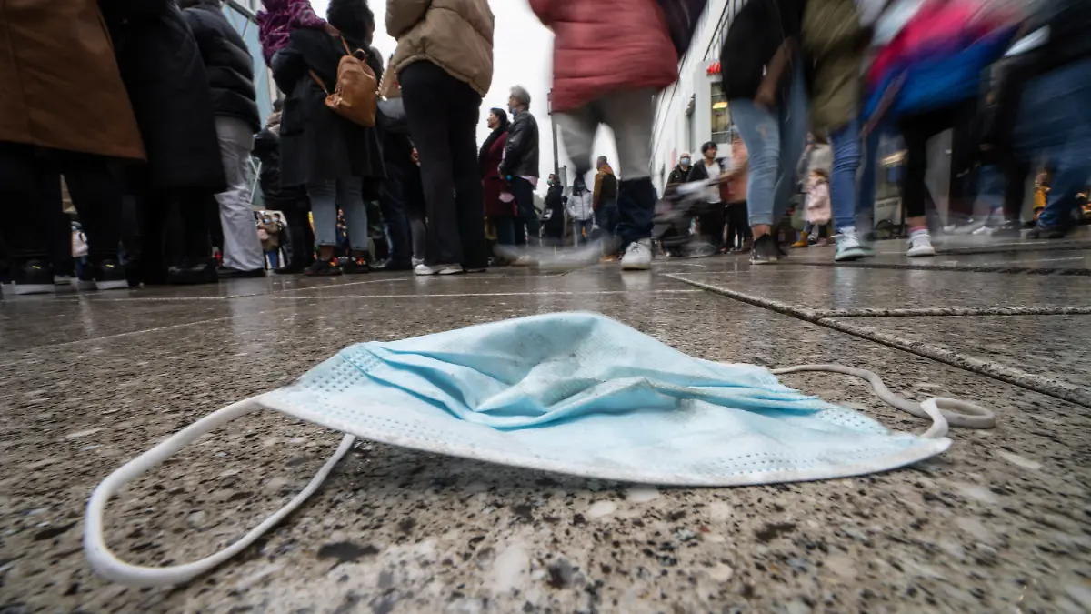 30.10.2021, Hessen, Frankfurt/Main: Ein verlorener Mund-Nasen-Schutz liegt am Nachmittag auf dem nassen Pflaster von Frankfurts zentraler Einkaufsmeile, der Zeil. Die Sieben-Tage-Inzidenz der Corona-Infektionen in Hessen ist am gleichen Tag (30.10.2021) weiter gestiegen. (Aufnahme mit längerer belichtungszeit und absichtlicher Bewegung der Kamera) Foto: Frank Rumpenhorst/dpa +++ dpa-Bildfunk +++