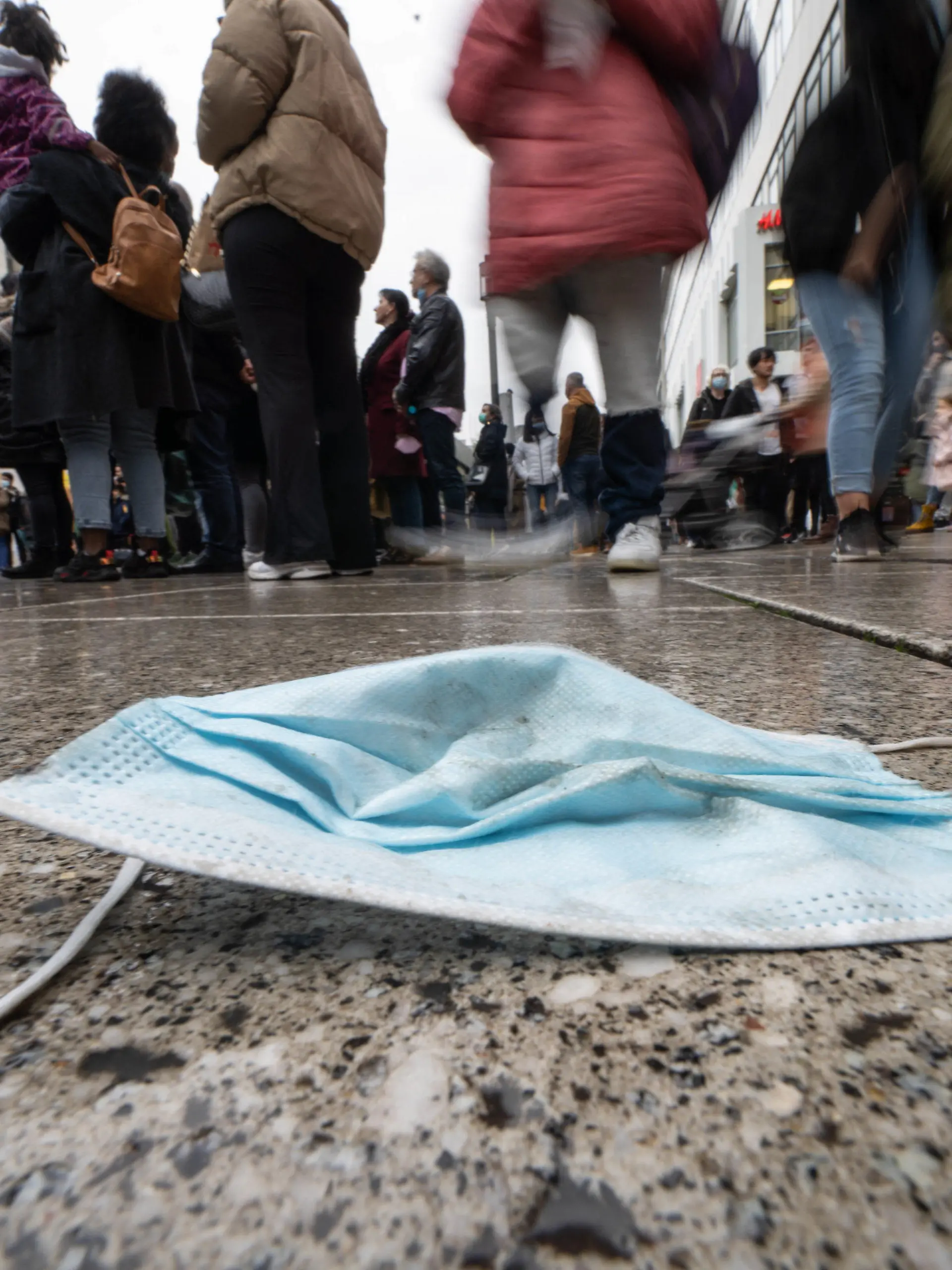 30.10.2021, Hessen, Frankfurt/Main: Ein verlorener Mund-Nasen-Schutz liegt am Nachmittag auf dem nassen Pflaster von Frankfurts zentraler Einkaufsmeile, der Zeil. Die Sieben-Tage-Inzidenz der Corona-Infektionen in Hessen ist am gleichen Tag (30.10.2021) weiter gestiegen. (Aufnahme mit längerer belichtungszeit und absichtlicher Bewegung der Kamera) Foto: Frank Rumpenhorst/dpa +++ dpa-Bildfunk +++