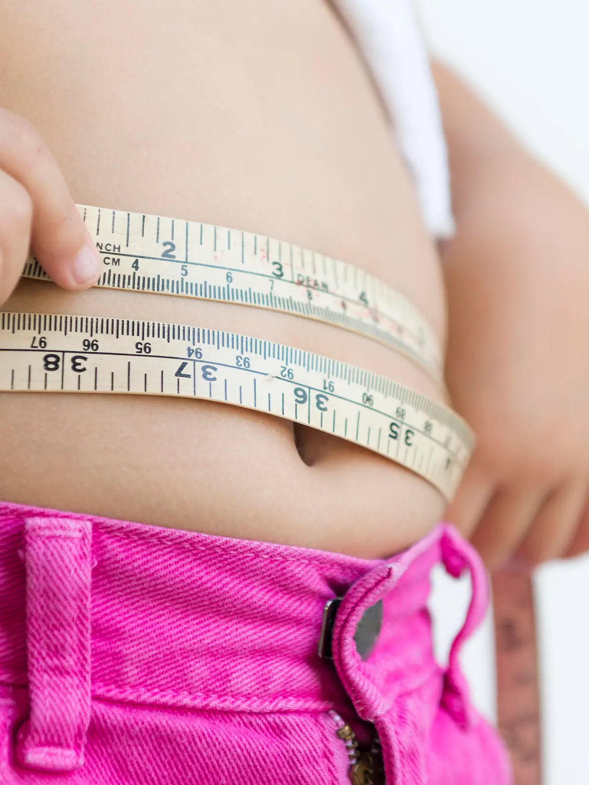 cute girl measuring her belly with measurement tape at home