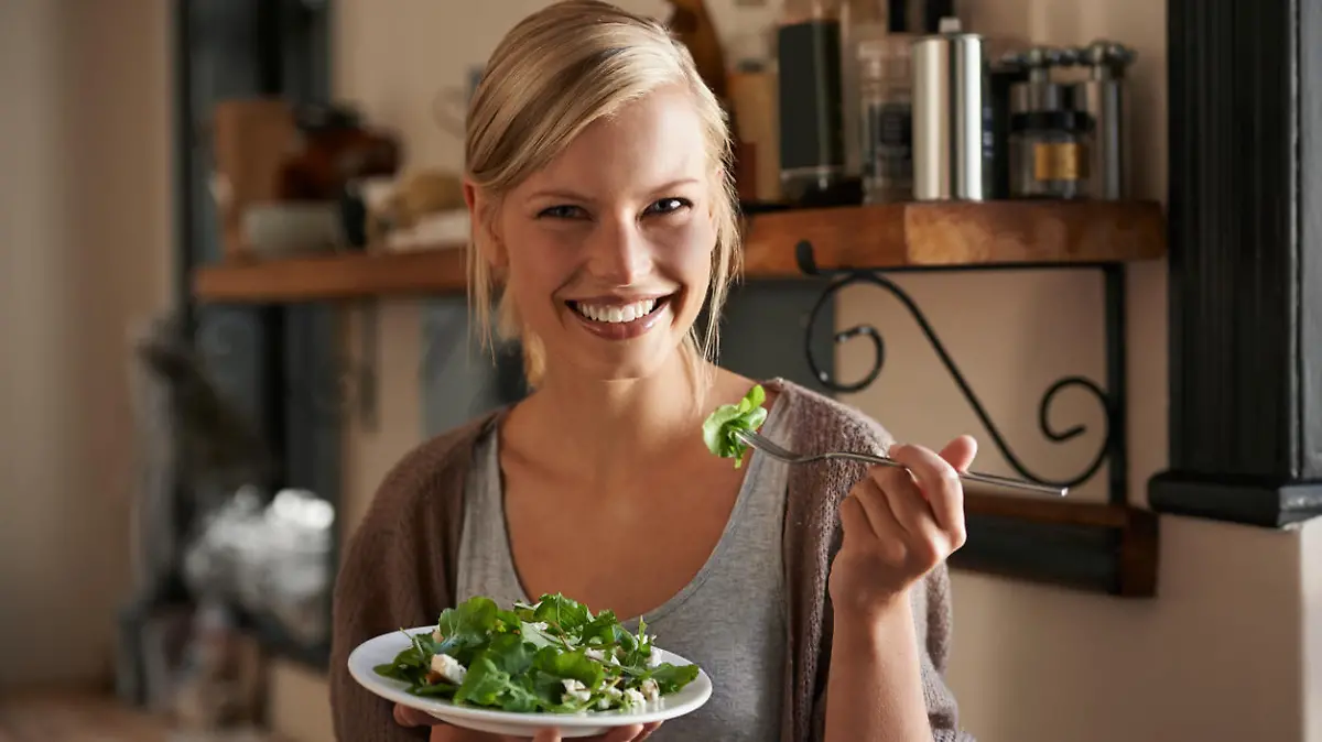 Portrait of an attractive young woman eating a salad in her kitchen