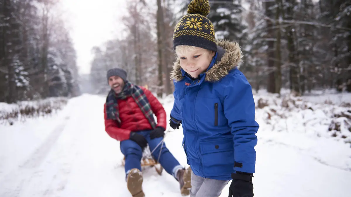 Portrait of little boy pulling his father sitting on sledge model released Symbolfoto PUBLICATIONxINxGERxSUIxAUTxHUNxONLY ABIF01141  