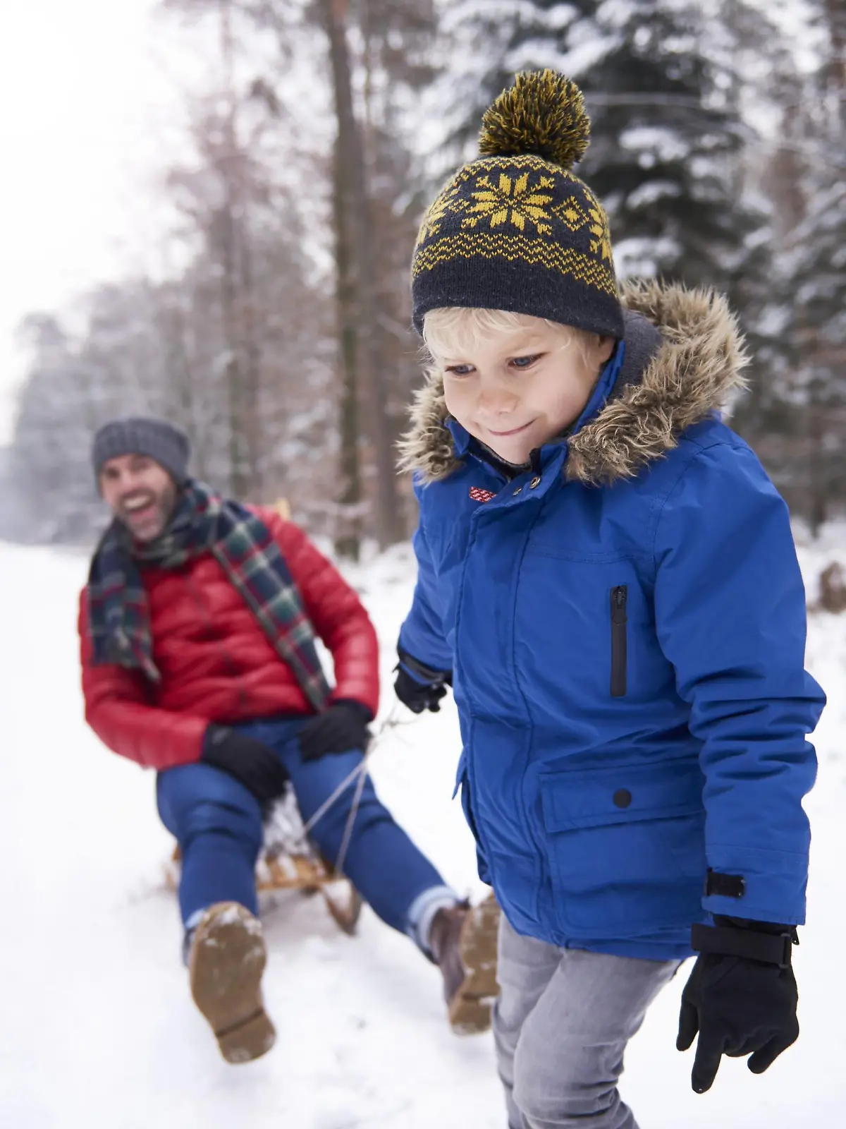 Portrait of little boy pulling his father sitting on sledge model released Symbolfoto PUBLICATIONxINxGERxSUIxAUTxHUNxONLY ABIF01141  