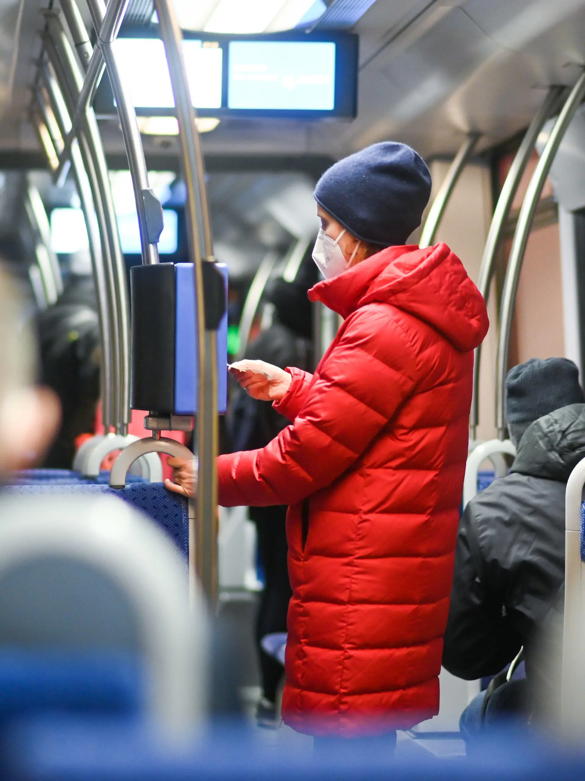 ILLUSTRATION - 18.01.2021, Bayern, München: In einer arrangierten Situation trägt eine Frau eine FFP2-Maske und stempelt eine Fahrkarte in einer Trambahn. In Bayern gilt ab dem 18.01.2021 an eine Pflicht zum Tragen von FFP2-Masken im öffentlichen Nahverkehr und im Einzelhandel. Foto: Tobias Hase/dpa +++ dpa-Bildfunk +++
