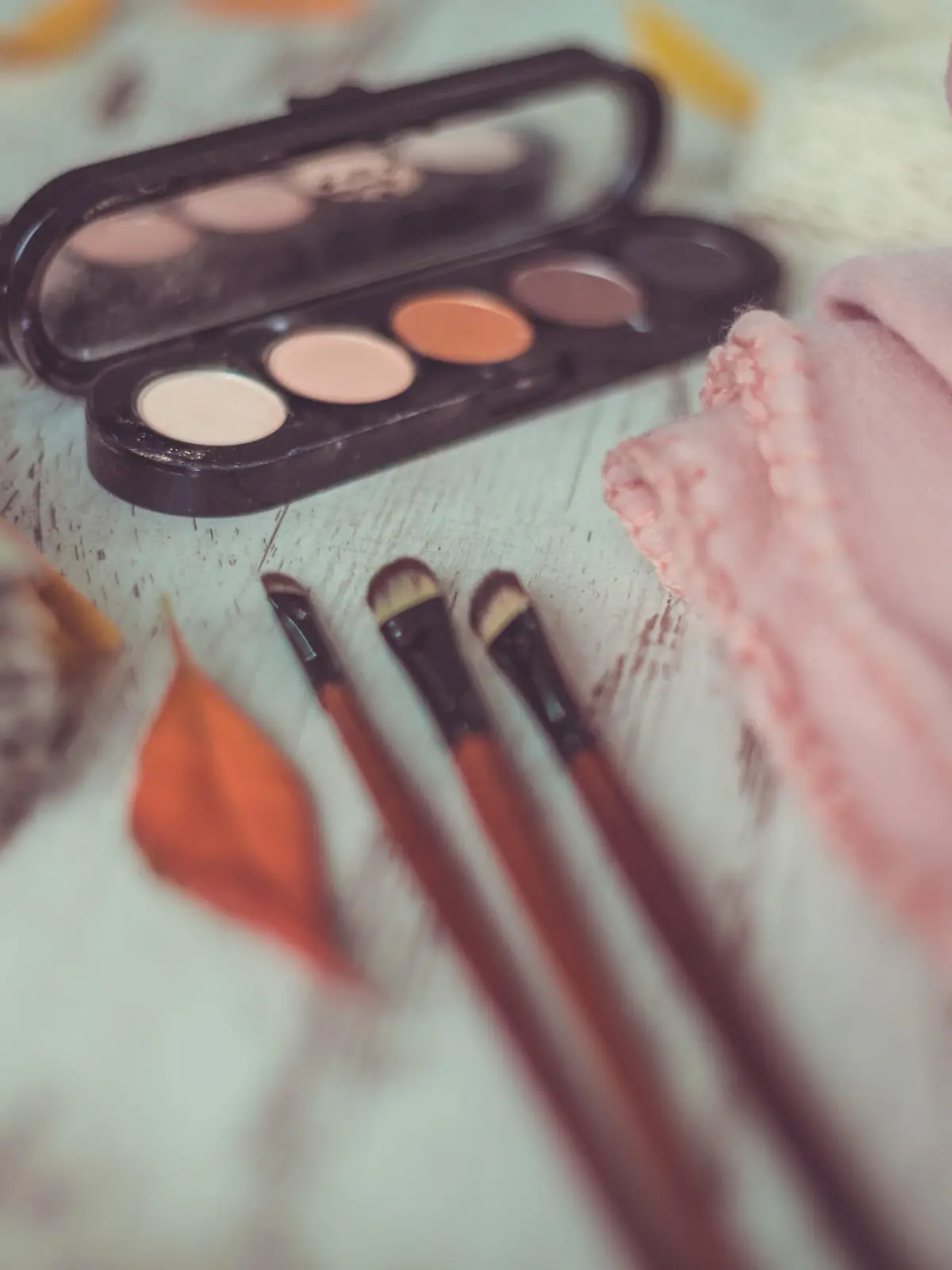 Close-up shot of eye shadow palette and make-up brushes on rustic table.