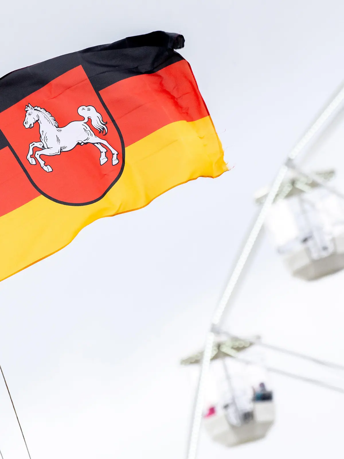 ARCHIV - 22.05.2021, Niedersachsen, Bensersiel: Eine niedersächsische Flagge weht vor einem Riesenrad im Hafen von Bensersiel an der Nordseeküste. Das Bundesland Niedersachsen feiert am 1. November sein 75-jähriges Bestehen. (Zu dpa: «Historiker: Niedersachsen ist erfolgreiche Integrationsgeschichte») Foto: Hauke-Christian Dittrich/dpa +++ dpa-Bildfunk +++