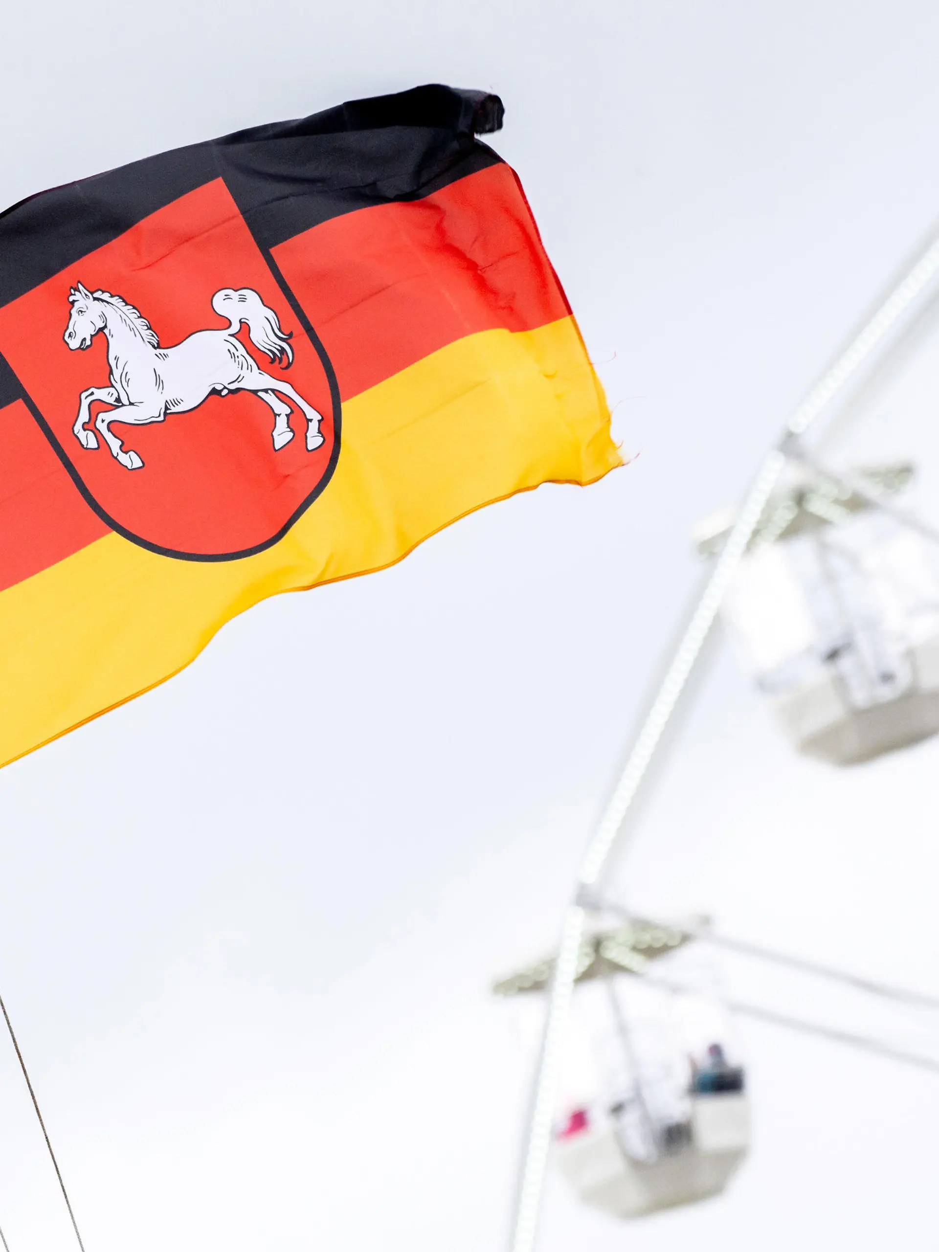 ARCHIV - 22.05.2021, Niedersachsen, Bensersiel: Eine niedersächsische Flagge weht vor einem Riesenrad im Hafen von Bensersiel an der Nordseeküste. Das Bundesland Niedersachsen feiert am 1. November sein 75-jähriges Bestehen. (Zu dpa: «Historiker: Niedersachsen ist erfolgreiche Integrationsgeschichte») Foto: Hauke-Christian Dittrich/dpa +++ dpa-Bildfunk +++