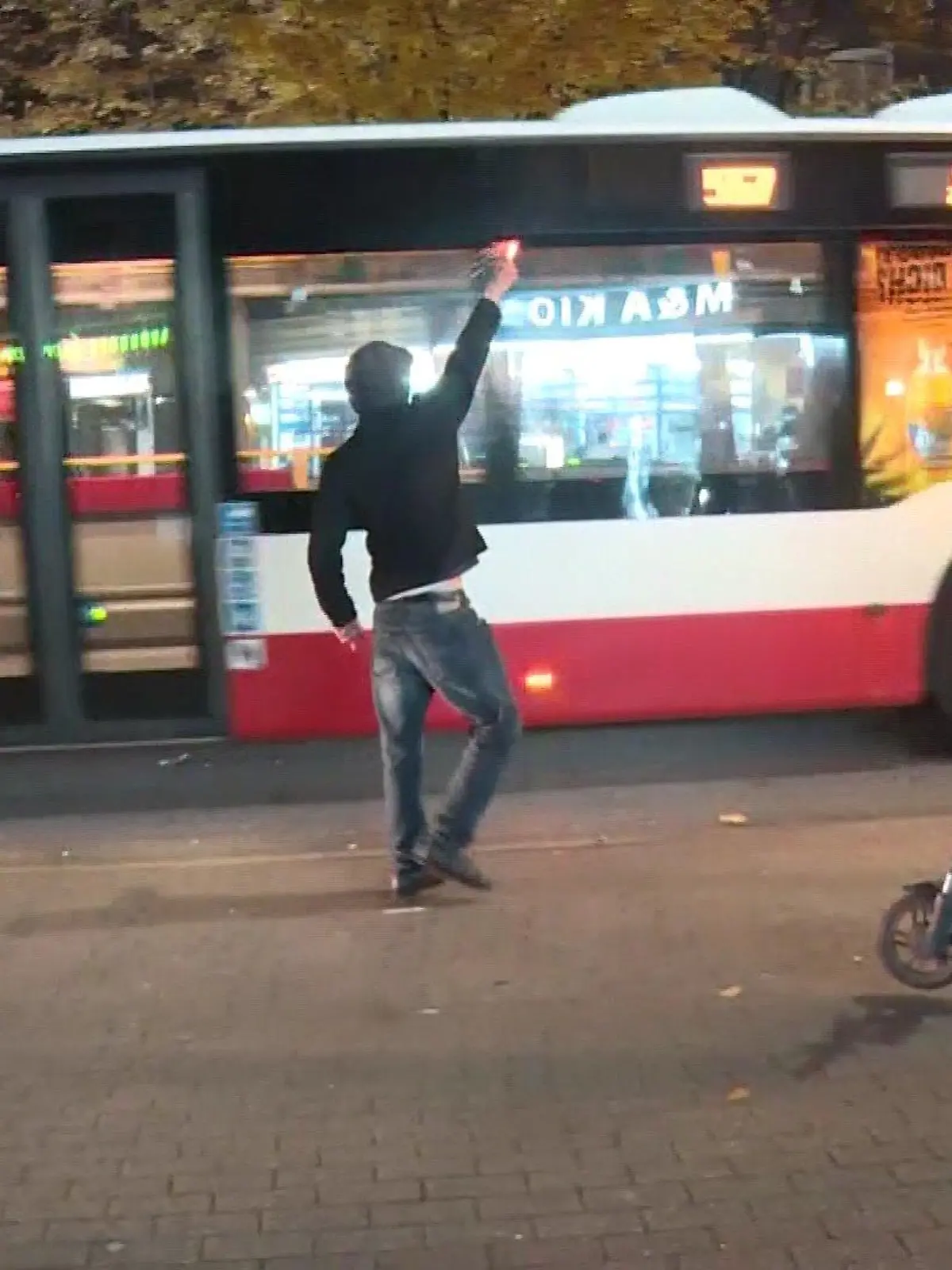 Ein Randalierer hält einen Böller in die Luft.