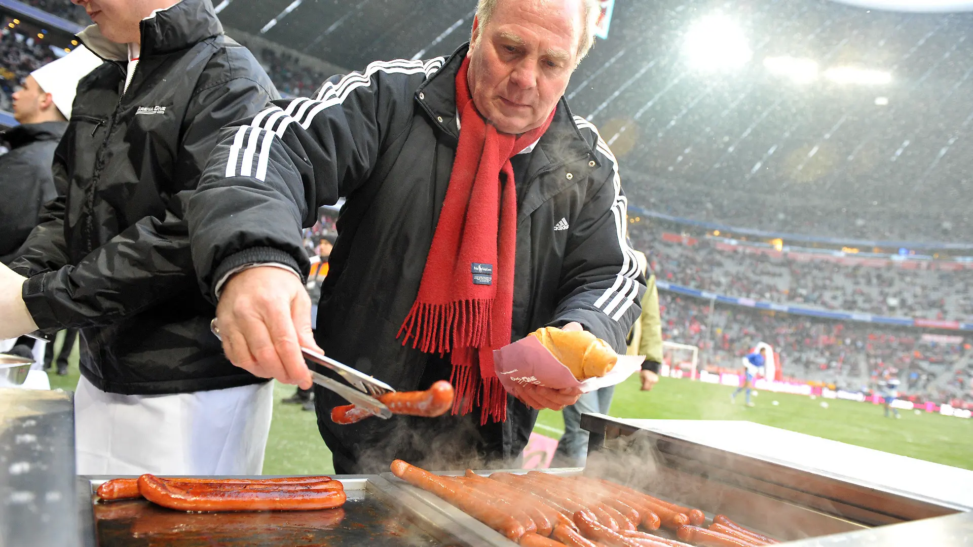ARCHIV - Fußball Bundesliga 17. Spieltag: FC Bayern München - Hertha BSC am 19.12.2009 in der Allianz Arena in München (Oberbayern). Münchens Präsident Uli Hoeneß verteilt vor Spielbeginn, aufgrund einer verlorenen Wette, Würstchen an die Fans. Bayern gewann die Partie mit 5:2. Der im Visier der Steuerfahnder stehende Bayern-Präsident Uli Hoeneß droht Medien mit juristischen Schritten. Schnelle Aufklärung ist nicht in Sicht: «Es müssen viele Dinge geprüft werden», sagte der ermittelnde Staatsanwalt. Die Branche äußert sich «geschockt». Foto: Andreas Gebert/dpa (zu dpa-Korr: «Hoeneß will sich «zur Wehr setzen» - Dauer der Untersuchungen offen » vom 22.04.2013) +++(c) dpa - Bildfunk+++