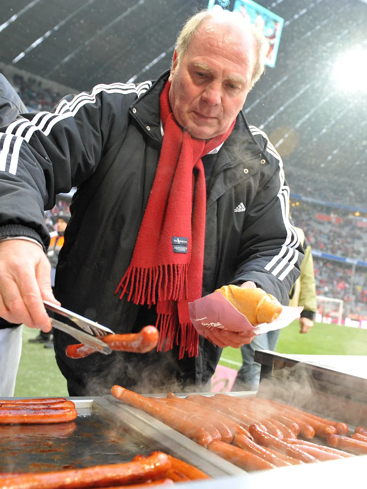 ARCHIV - Fußball Bundesliga 17. Spieltag: FC Bayern München - Hertha BSC am 19.12.2009 in der Allianz Arena in München (Oberbayern). Münchens Präsident Uli Hoeneß verteilt vor Spielbeginn, aufgrund einer verlorenen Wette, Würstchen an die Fans. Bayern gewann die Partie mit 5:2. Der im Visier der Steuerfahnder stehende Bayern-Präsident Uli Hoeneß droht Medien mit juristischen Schritten. Schnelle Aufklärung ist nicht in Sicht: «Es müssen viele Dinge geprüft werden», sagte der ermittelnde Staatsanwalt. Die Branche äußert sich «geschockt». Foto: Andreas Gebert/dpa (zu dpa-Korr: «Hoeneß will sich «zur Wehr setzen» - Dauer der Untersuchungen offen » vom 22.04.2013) +++(c) dpa - Bildfunk+++
