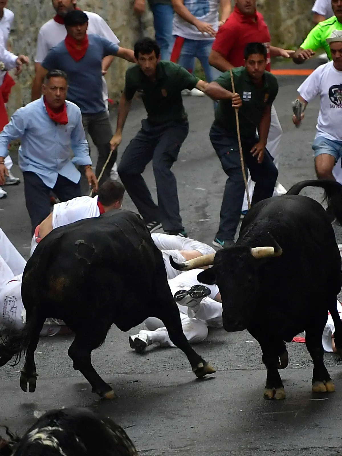 07.07.2018, Spanien, Pamplona: Teilnehmer der  Stierhatz treiben zwei Stiere durch die Gassen von Pamplona. Bis zum 14. Juli werden während des «Sanfermines»-Festes täglich am frühen Vormittag Kampfbullen und Leitochsen von Hunderten von Männern und wenigen Frauen, für die Stierkämpfe am Abend, durch die Gassen in die Arena gejagt. Foto: Alvaro Barrientos/AP/dpa +++ dpa-Bildfunk +++