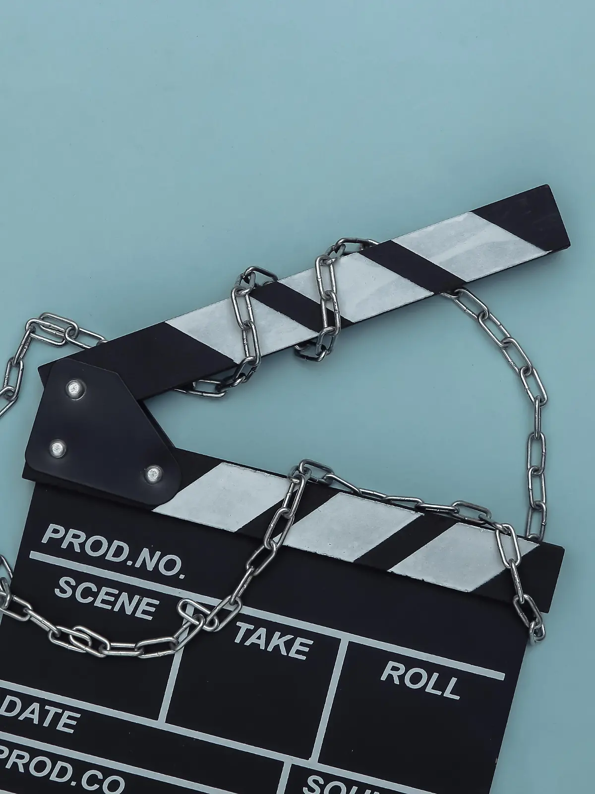 Movie clapperboard wrapped in steel chain on blue background. Ban on filmmaking. Top view