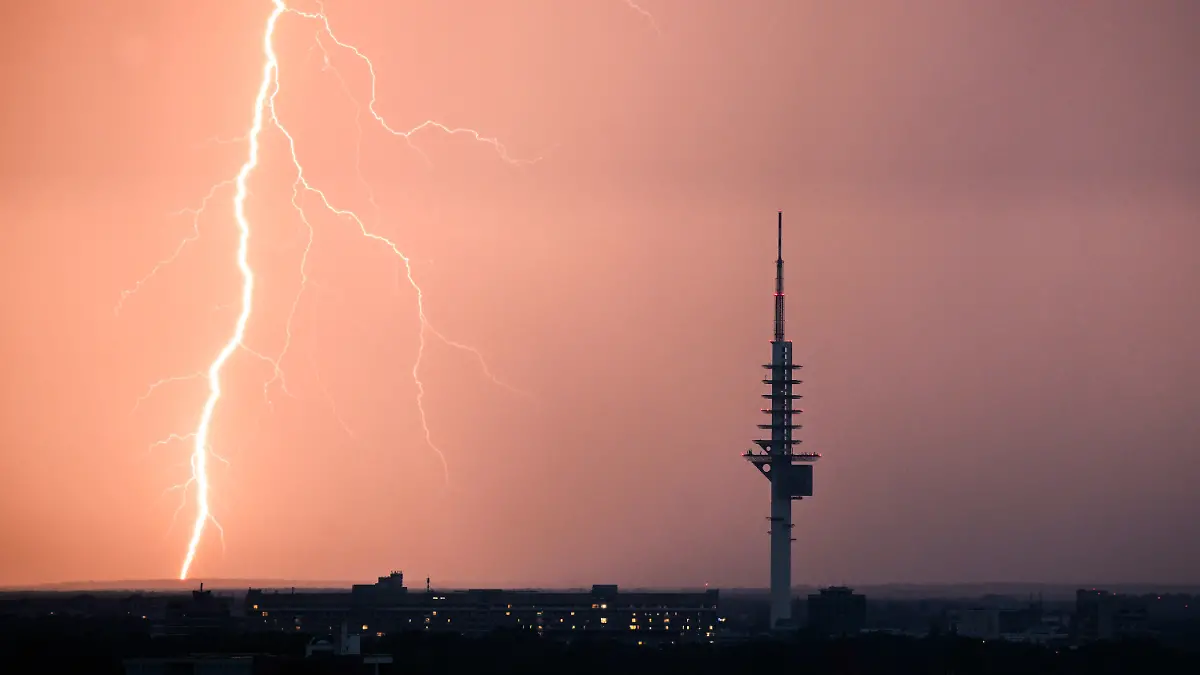 ARCHIV - 09.07.2023, Niedersachsen, Hannover: Ein Blitz entlädt sich während eines Gewitters hinter dem Fernmeldeturm Telemax in Hannover.      (zu dpa «20 Warnungen via Cell Broadcast in Niedersachsen») Foto: Julian Stratenschulte/dpa +++ dpa-Bildfunk +++