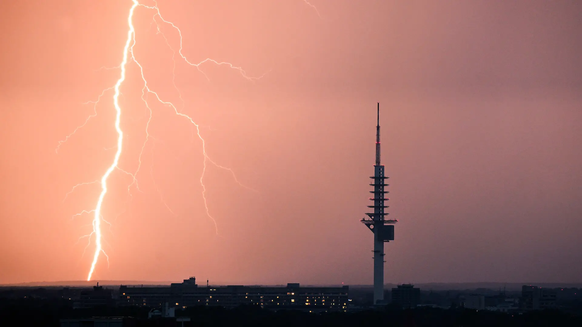 ARCHIV - 09.07.2023, Niedersachsen, Hannover: Ein Blitz entlädt sich während eines Gewitters hinter dem Fernmeldeturm Telemax in Hannover. (zu dpa «20 Warnungen via Cell Broadcast in Niedersachsen») Foto: Julian Stratenschulte/dpa +++ dpa-Bildfunk +++