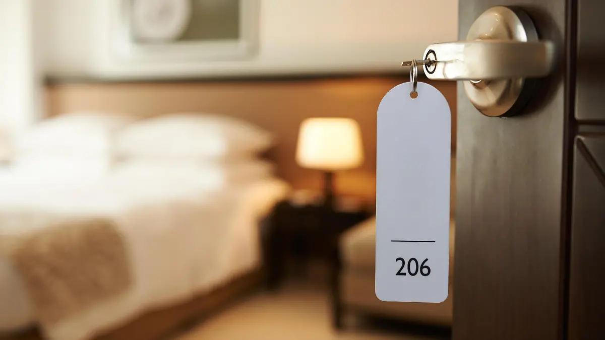 Opened door of hotel room with key in the lock