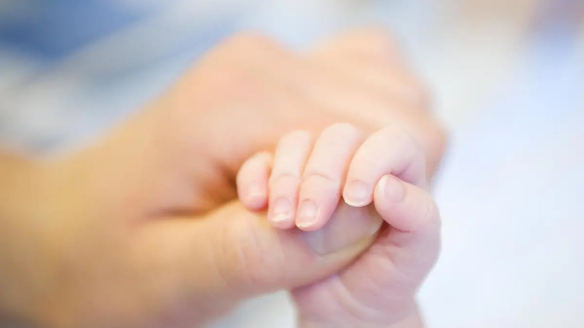 Parent hand holding baby's leg