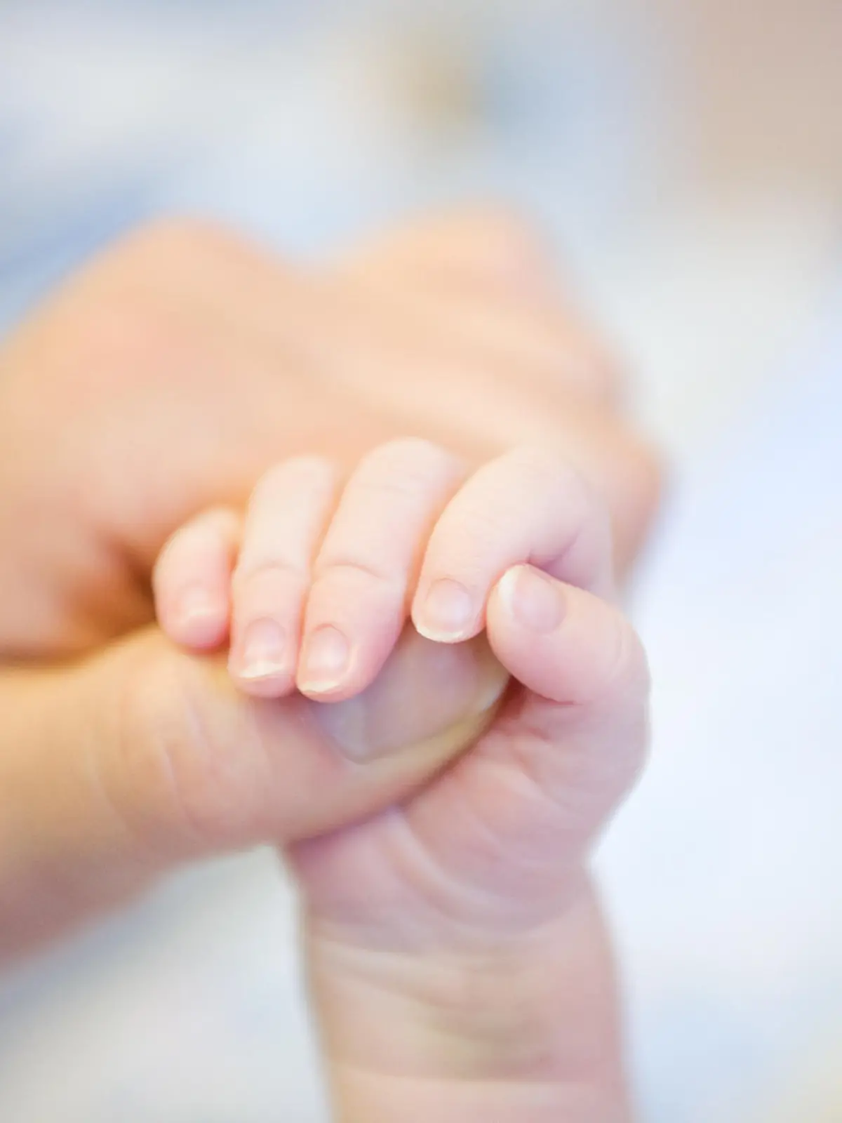 Parent hand holding baby's leg
