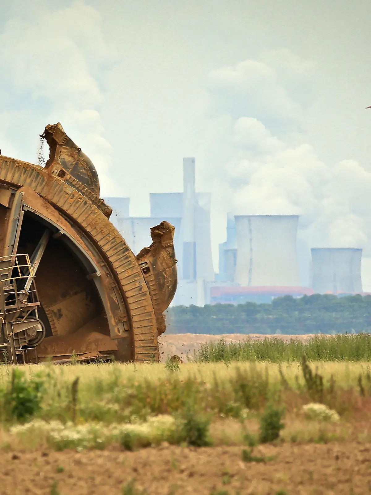 ARCHIV - 20.06.2019, Nordrhein-Westfalen, Jackerath: Der Schaufel eines Braunkohlebaggers baggert im Tagebau Garzeiler; im Hintergrund stehen eines der RWE-Kraftwerke und daneben Windräder. (zu dpa Themenpaket Weltklimakonferenz COP26 in Glasgow) Foto: David Young/dpa +++ dpa-Bildfunk +++