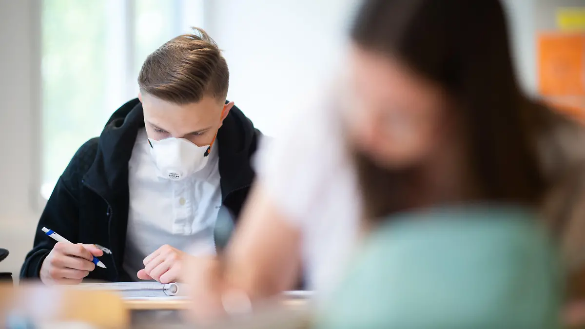 ARCHIV - 23.04.2020, Nordrhein-Westfalen, Übach-Palenberg: Schülerinnen und Schüler, einer davon mit einer Schutzmaske, bearbeiten Informatikaufgaben im Informatik-Grundkurs des Abiturjahrgangs am Carolus-Magnus-Gymnasium. Schüler ab der 5. Klasse müssen in Nordrhein-Westfalen nach den Herbstferien auch an ihrem Sitzplatz im Unterricht wieder Maske tragen. Die Regelung soll bis zu den Weihnachtsferien gelten, teilte das Schulministerium am Mittwoch in einer Mail an alle Schulen mit. (zu dpa «NRW führt Maskenpflicht für Schüler auch im Unterricht wieder ein») Foto: Jonas Güttler/dpa +++ dpa-Bildfunk +++