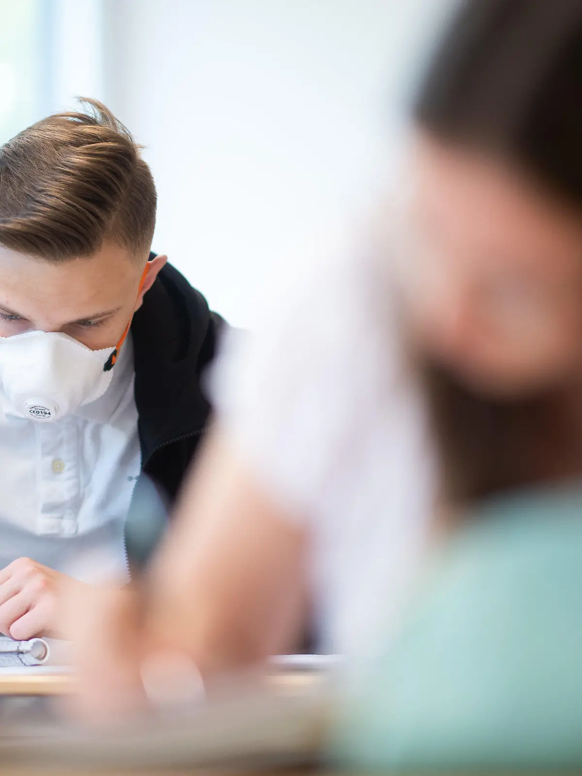 ARCHIV - 23.04.2020, Nordrhein-Westfalen, Übach-Palenberg: Schülerinnen und Schüler, einer davon mit einer Schutzmaske, bearbeiten Informatikaufgaben im Informatik-Grundkurs des Abiturjahrgangs am Carolus-Magnus-Gymnasium. Schüler ab der 5. Klasse müssen in Nordrhein-Westfalen nach den Herbstferien auch an ihrem Sitzplatz im Unterricht wieder Maske tragen. Die Regelung soll bis zu den Weihnachtsferien gelten, teilte das Schulministerium am Mittwoch in einer Mail an alle Schulen mit. (zu dpa «NRW führt Maskenpflicht für Schüler auch im Unterricht wieder ein») Foto: Jonas Güttler/dpa +++ dpa-Bildfunk +++