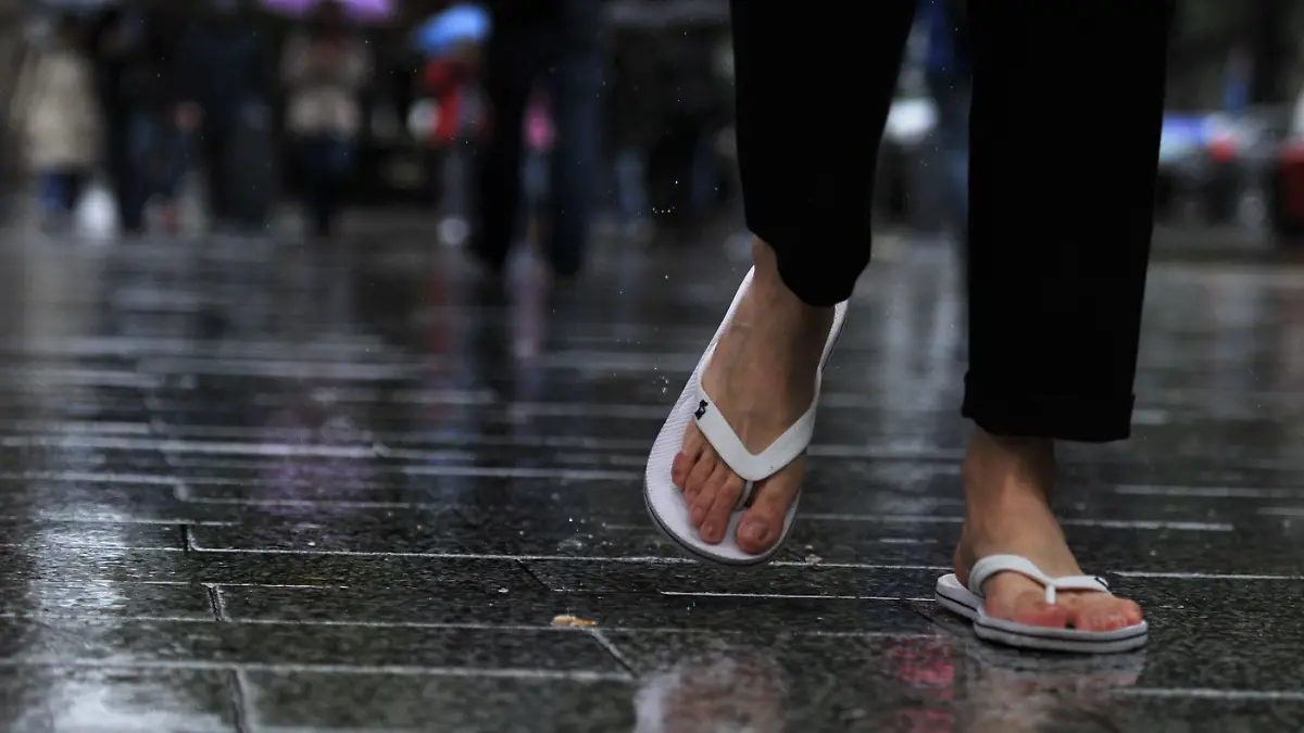 Ein junger Mann läuft am 09.07.2014 im Regen in Flipflops über die Königsallee in Düsseldorf (Nordrhein-Westfalen). Foto: Matthias Balk/dpa +++(c) dpa - Bildfunk+++