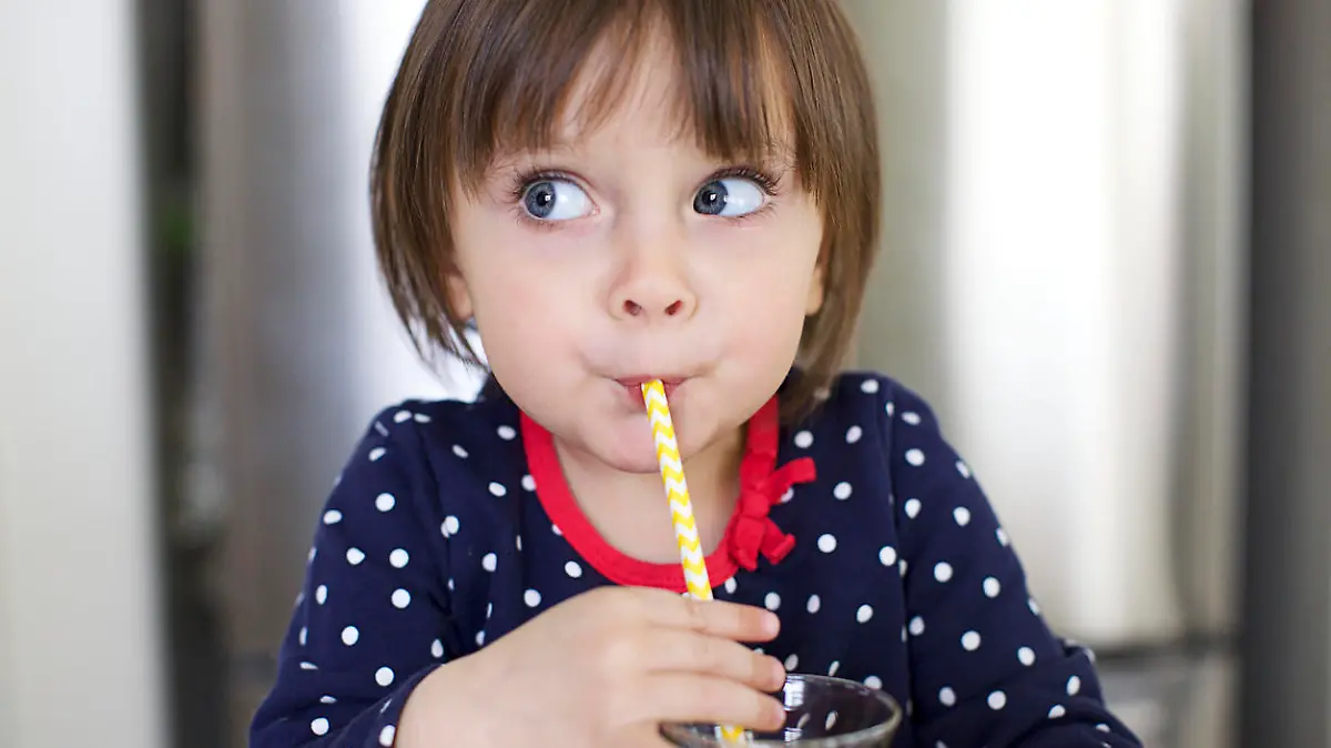 Cute Little Girl is Drinking Water With a Paper Straw and Making Faces