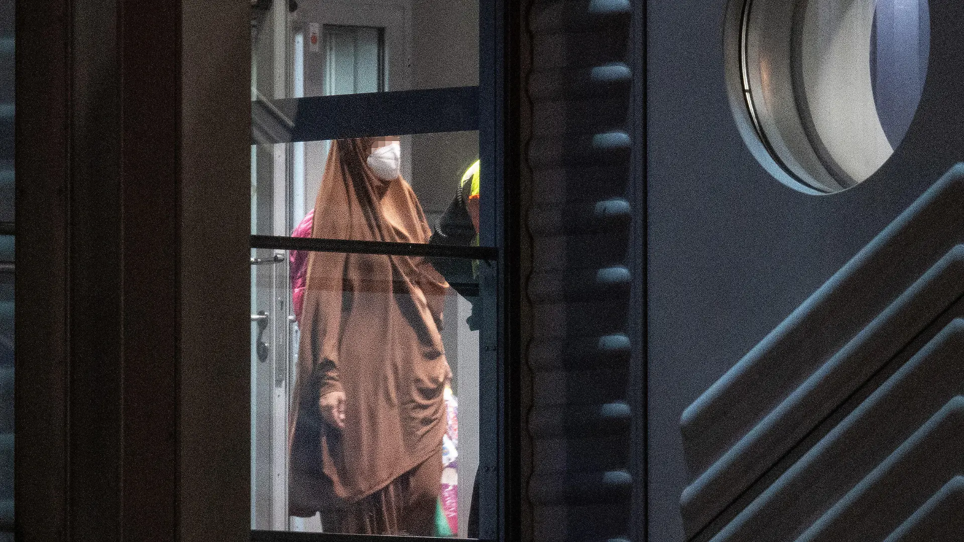 07.10.2021, Hessen, Frankfurt/Main: Eine verschleierte Frau mit einer Maske betritt aus der Gangway einer Chartermaschine heraus einen abgeschirmten Bereich der Bundespolizei am Flughafen Frankfurt. In einer zunächst geheim gehaltenen Aktion hatte die Bundesregierung in Zusammenarbeit mit der US-Armee insgesamt acht deutsche Anhängerinnen der Terrormiliz ·Islamischer Staat· (IS) mit ihren 23 Kindern im Rahmen einer humanitären Aktion aus einem Gefangenenlager in Syrien geholt. Mit einer Chartermaschine wurden die Frauen über Kuwait nach Deutschland gebracht, wo fast alle sofort in Haft genommen wurden. Foto: Boris Roessler/dpa +++ dpa-Bildfunk +++