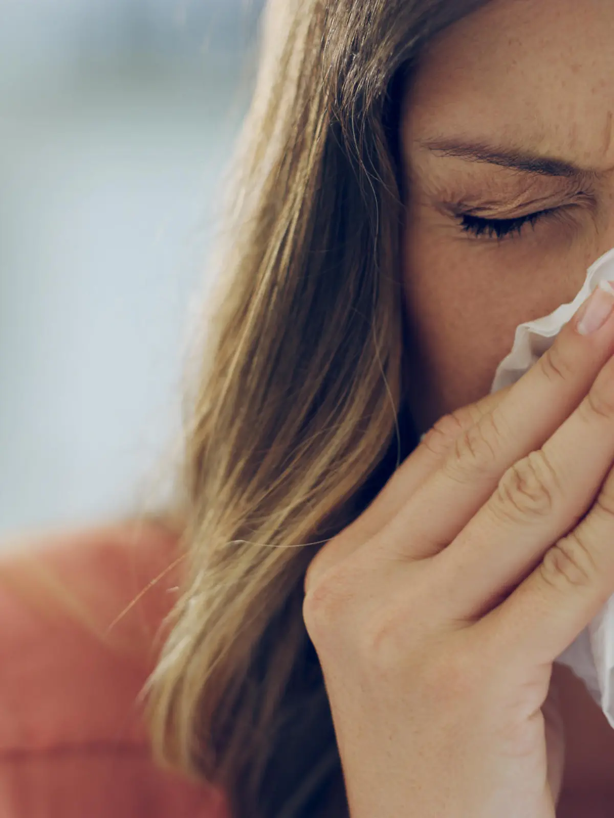 Shot of an attractive young woman feeling ill and blowing her nose with a tissue at home