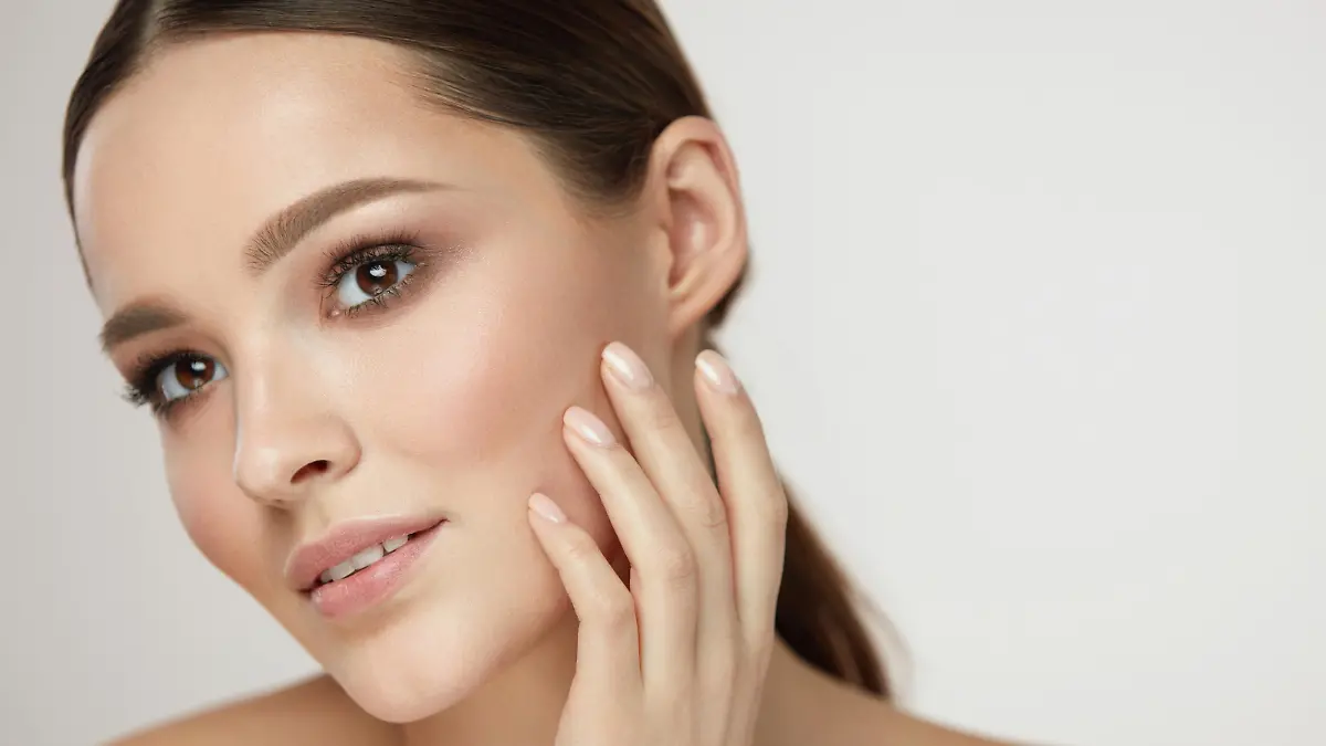 Cosmetic Face Care. Portrait Of Beautiful Girl Caressing Facial Skin Posing On Grey Background. Closeup Of Sexy Young Woman With Soft Clean Skin And Natural Makeup. Beauty Concept. High Resolution
