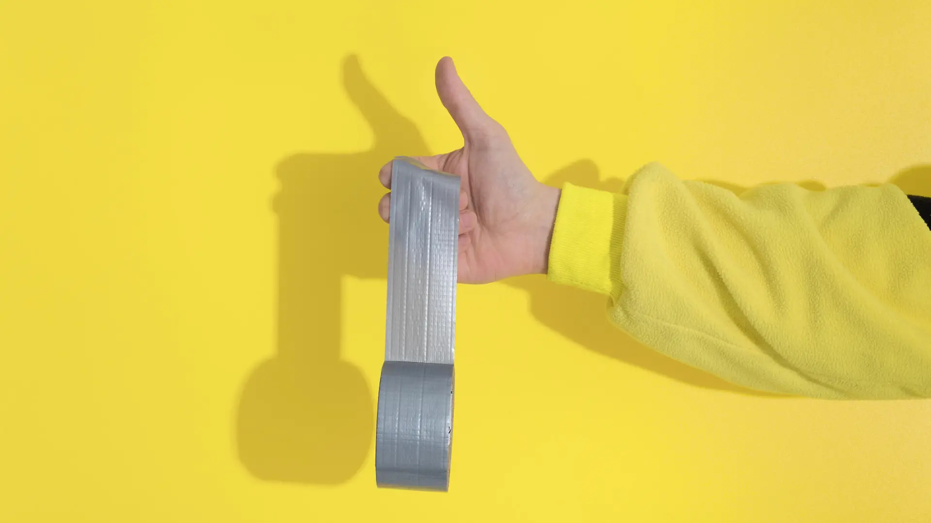 Male hand in yellow kugurumi holds Ultimate Gray tape sticks