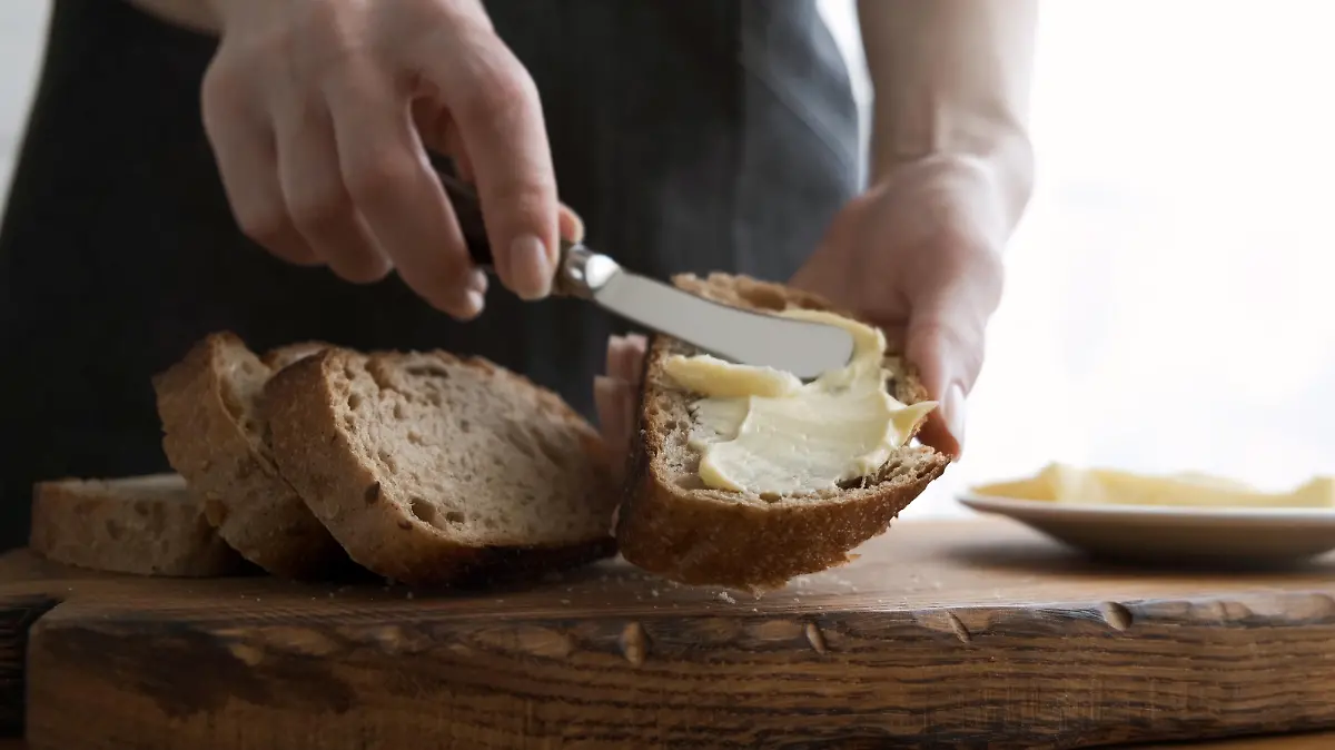 Spreading butter on bread. Woman's hands making sandwich with bread and butter