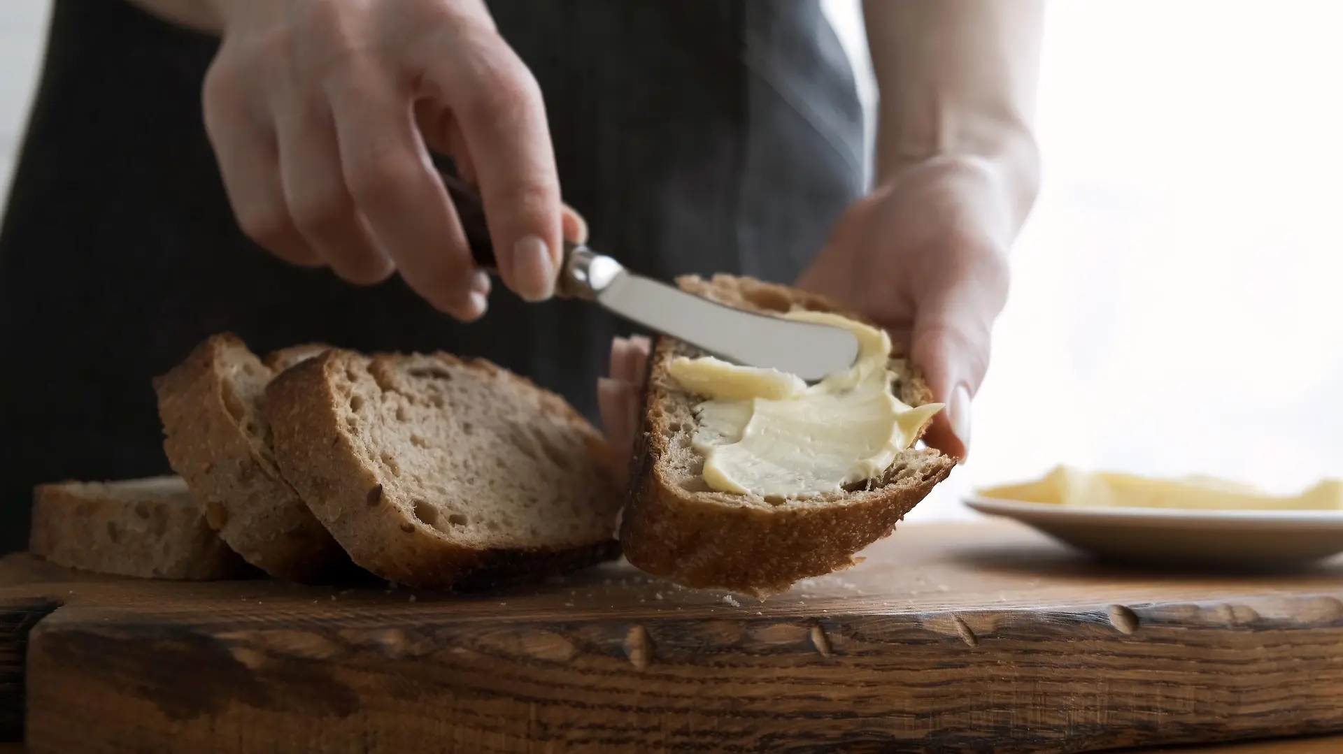 Spreading butter on bread. Woman's hands making sandwich with bread and butter