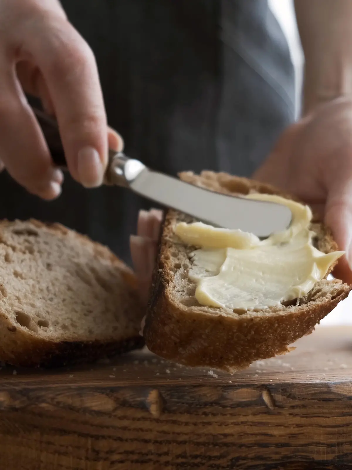 Spreading butter on bread. Woman's hands making sandwich with bread and butter