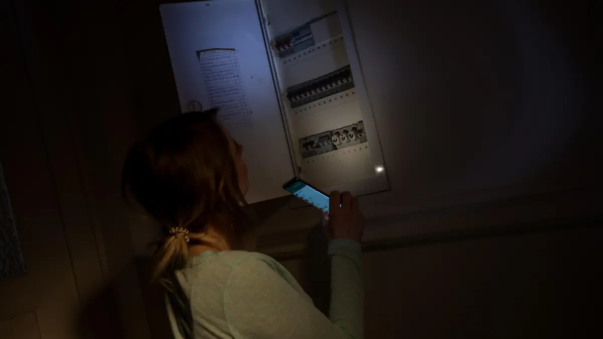 ILLUSTRATION - Eine junge Frau schaut am 29.01.2020 in einer Wohnung in Wittenberge waehrend eines Stromausfalls mit Hilfe der Taschenlampe auf ihrem Smartphone in den Sicherungskasten (gestellte Szene). Foto: Christin Klose