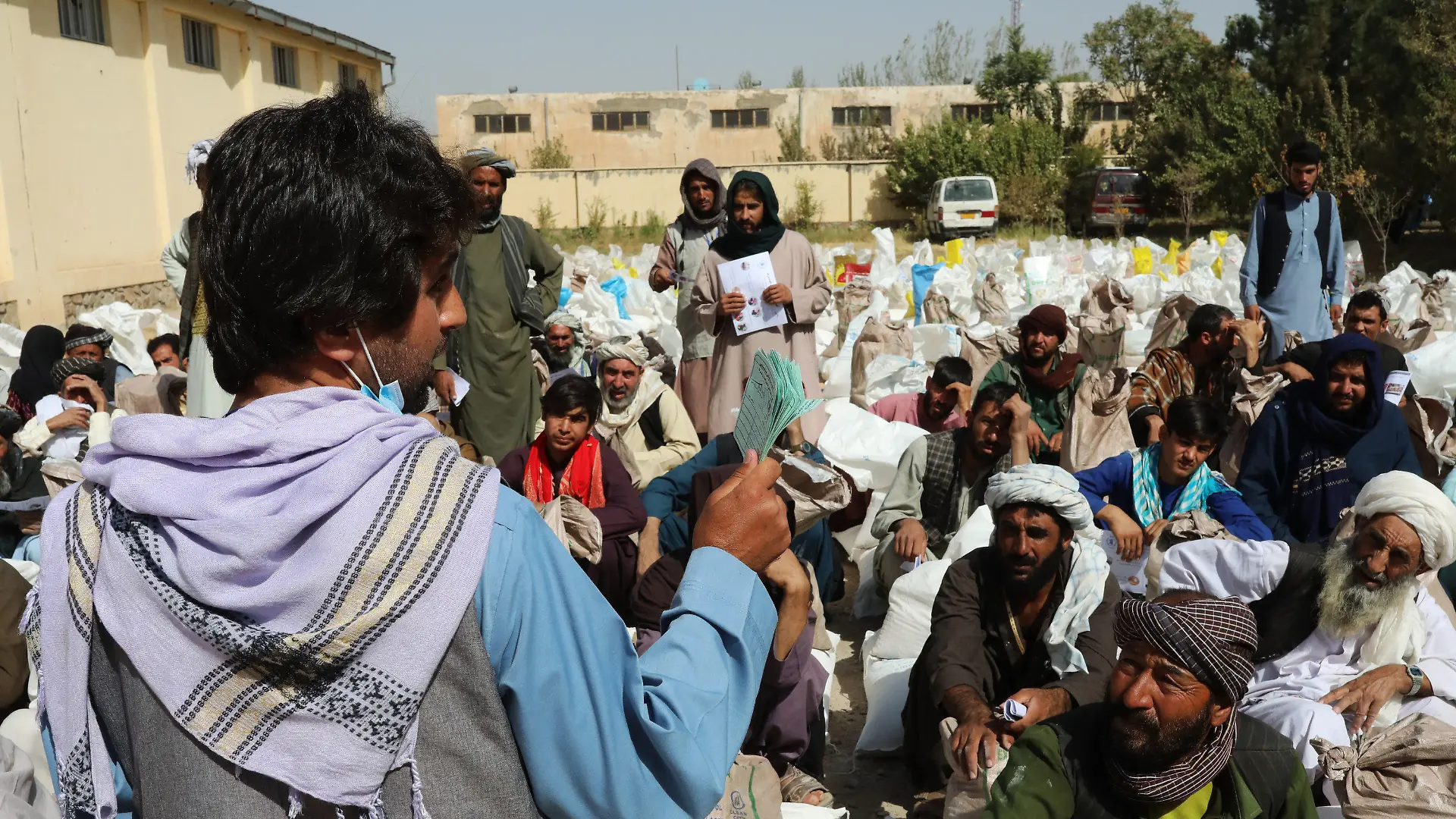 HANDOUT - 02.10.2021, Afghanistan, Herat: Ein Mitarbeiter eines Partners des Welternährungsprogramms WFP verteilt Nahrungsmitteln am Stadtrand. Die Rationen bestehen aus Weizenmehl, Erbsen, Öl und Salz für jede Familie. (zu dpa "Hälfte der afghanischen Bevölkerung von akutem Hunger bedroht") Foto: Marco Di Lauro/World Food Programm WFP/dpa - ACHTUNG: Nur zur redaktionellen Verwendung im Zusammenhang mit der aktuellen Berichterstattung und nur mit vollständiger Nennung des vorstehenden Credits +++ dpa-Bildfunk +++
