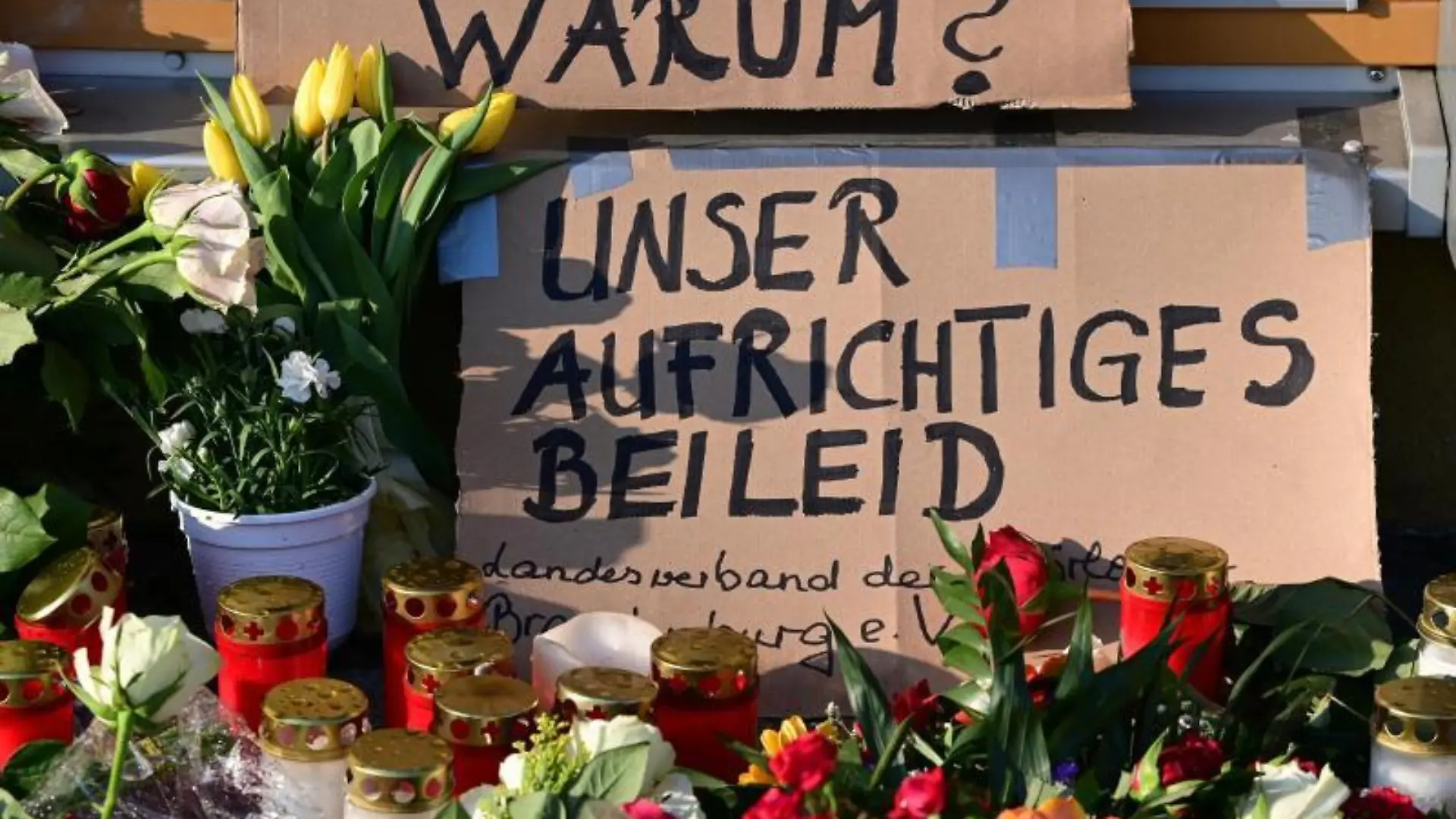 Blumen, Kerzen und ein Plakat liegen vor dem Oberlinhaus