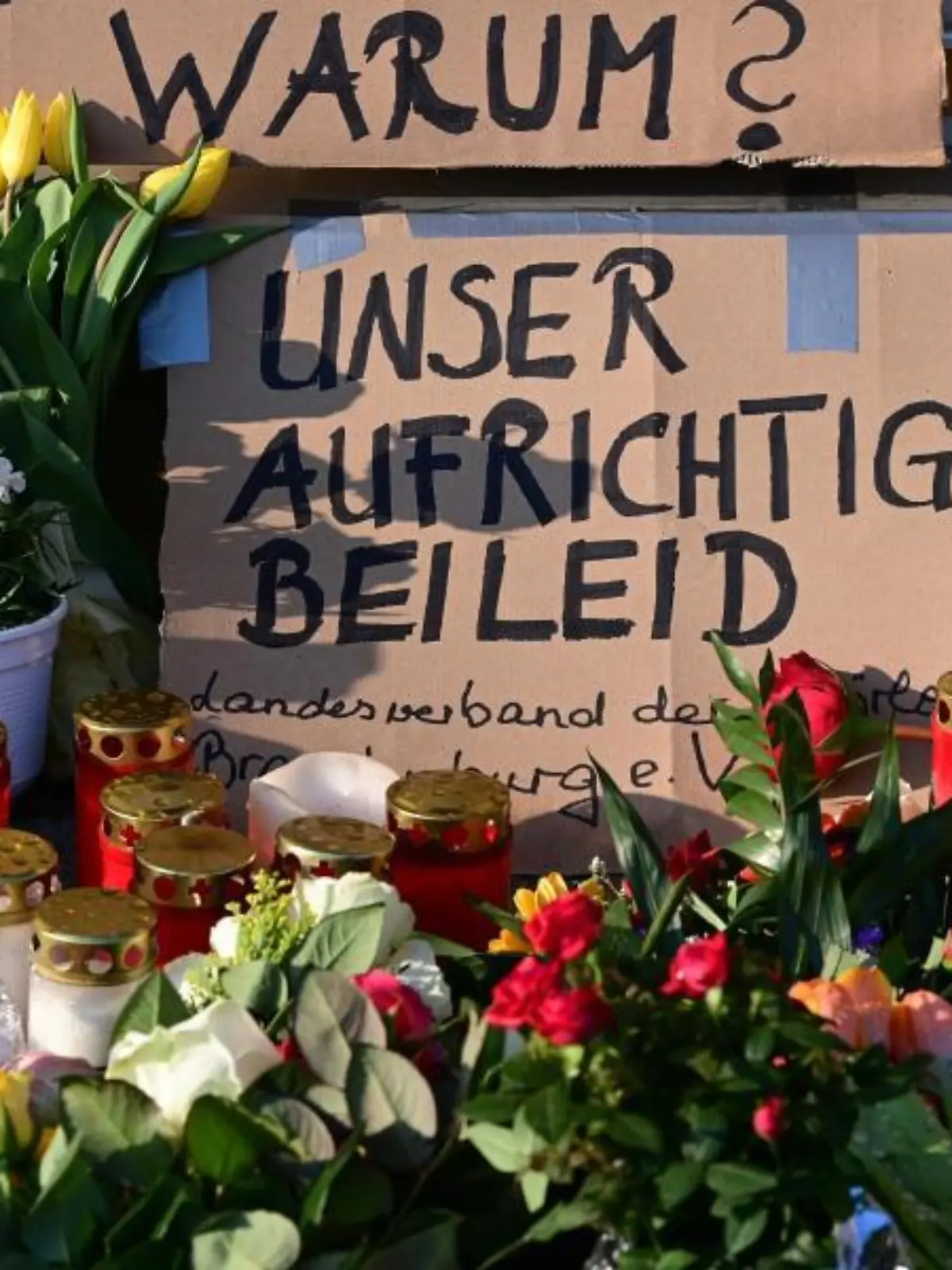 Blumen, Kerzen und ein Plakat liegen vor dem Oberlinhaus