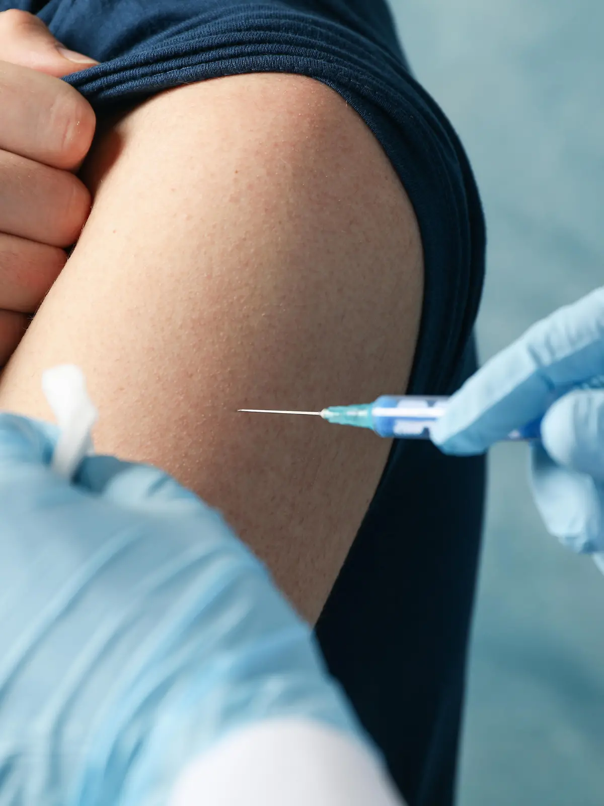 Doctor does an injection patient on blue background. Coronavirus protection. Healthcare and medical concept